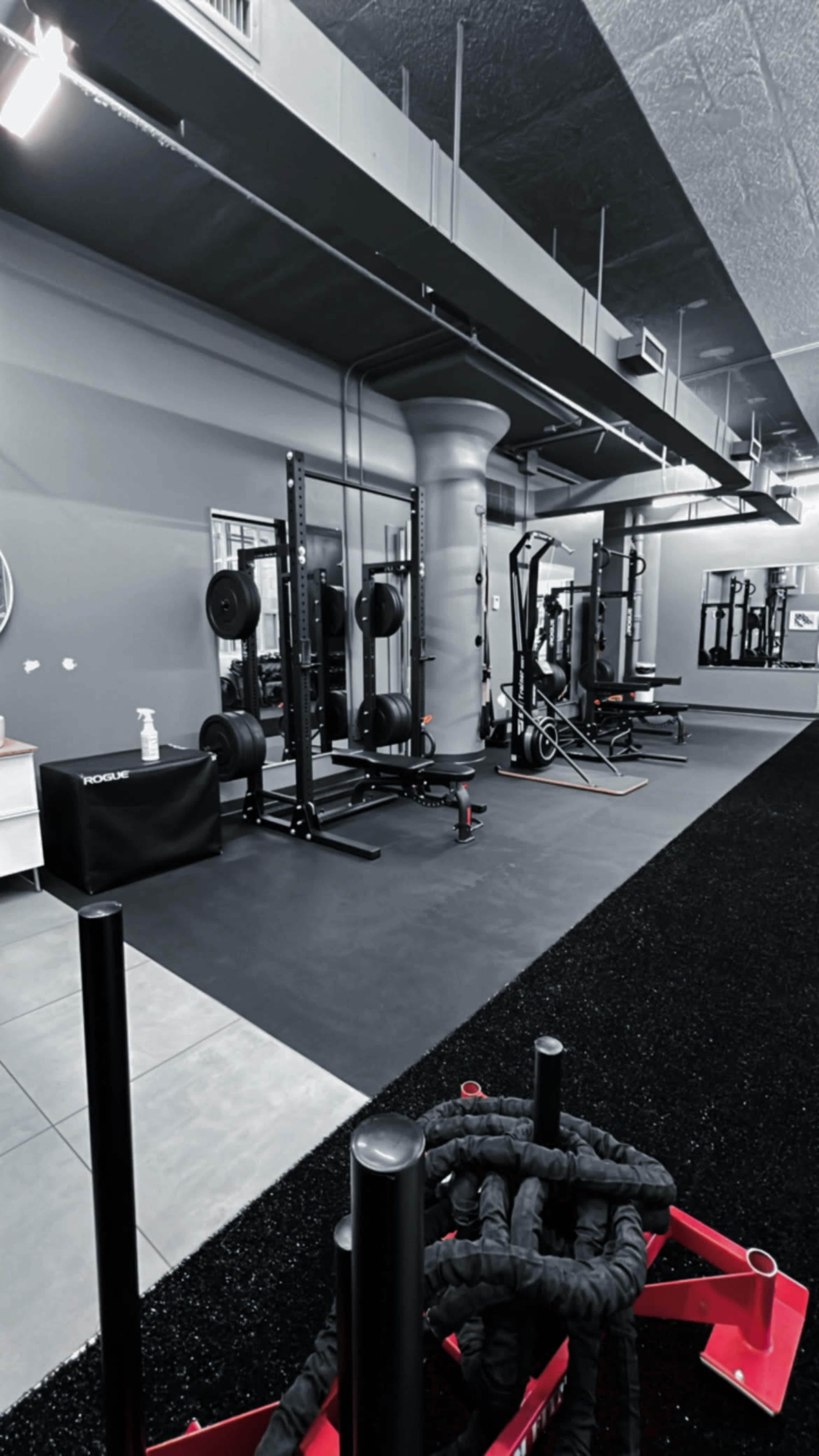 A gym interior featuring weightlifting equipment, a cable machine, and a rubberized floor.