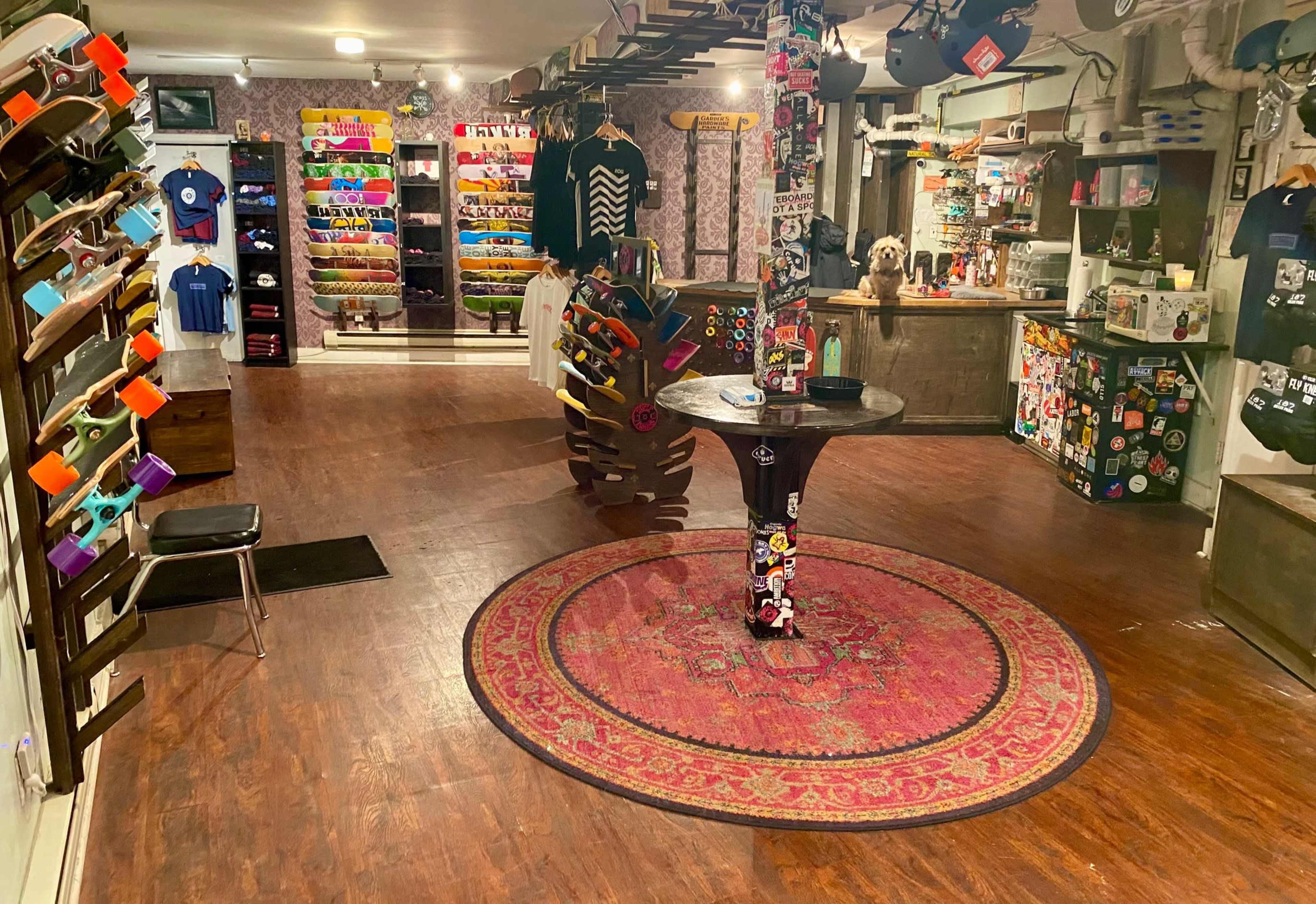 The interior of a skate shop featuring rows of skateboards, apparel, and accessories displayed on racks against a patterned wall.