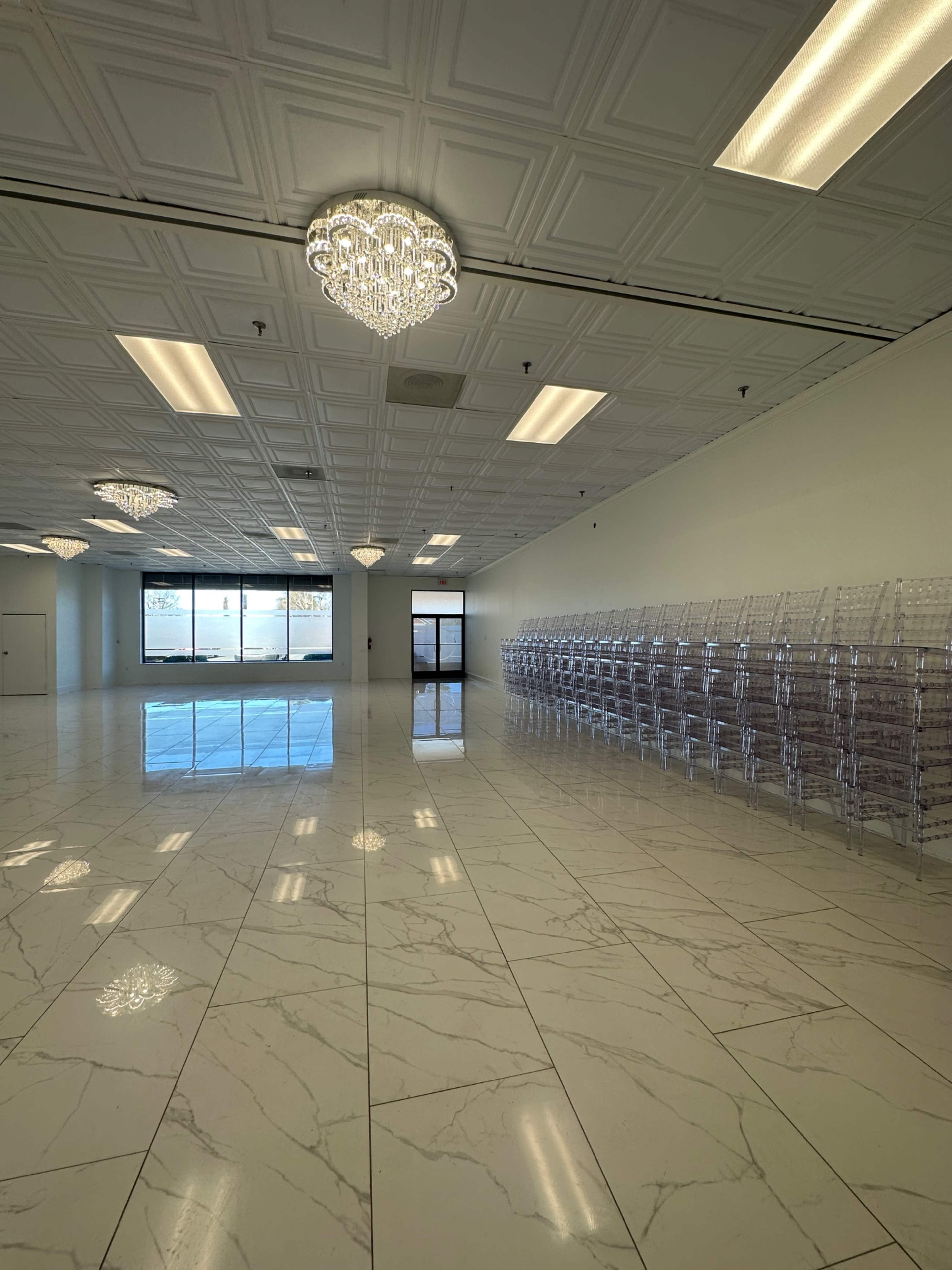 The image shows a spacious, empty room with marble flooring and rows of clear display bins along one wall.