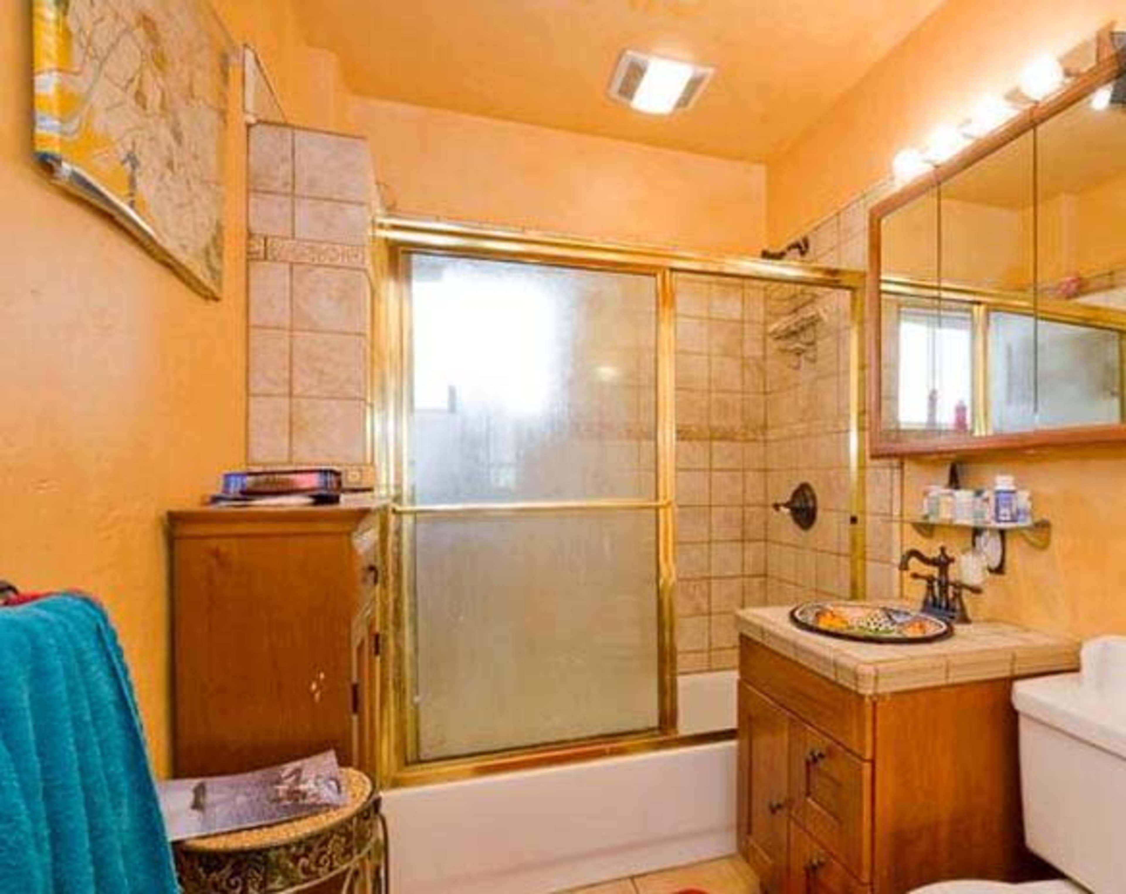 A bathroom featuring a bathtub with a shower, a vanity with a mirror, and peach-colored walls.