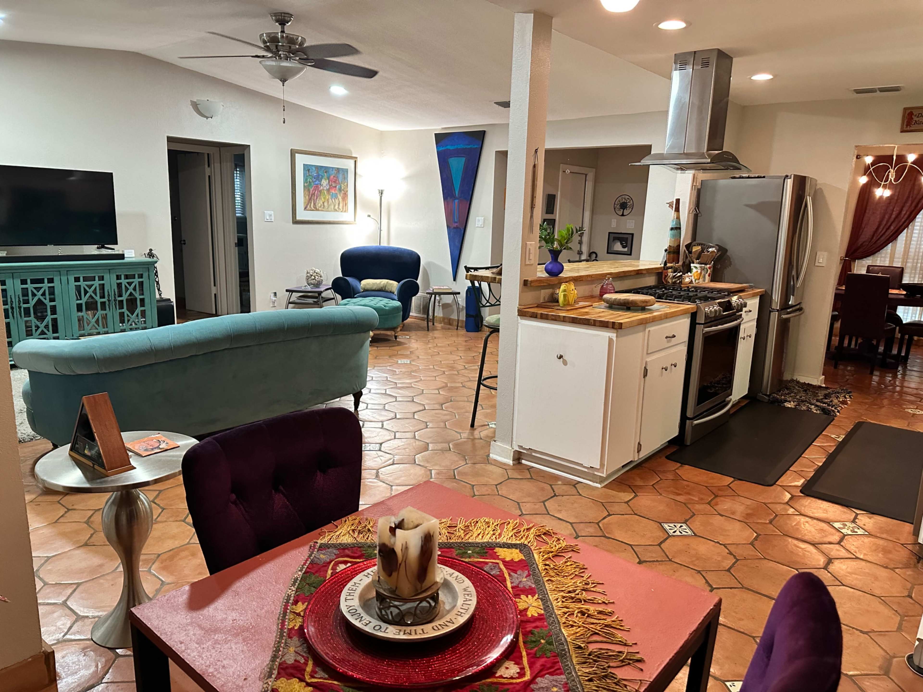 An open-concept living area with a kitchen, dining space, and a living room featuring various pieces of furniture and decorative elements.