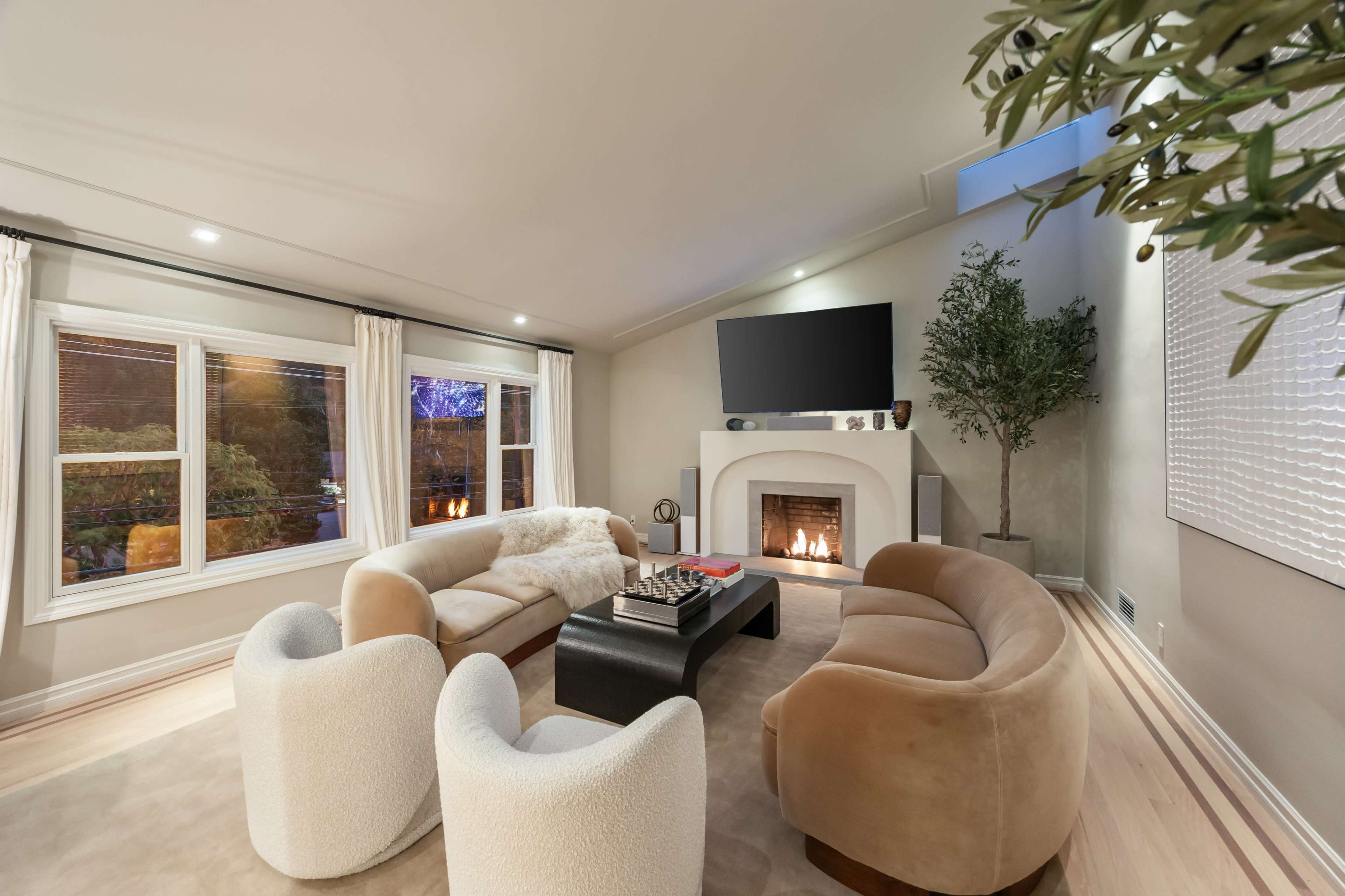 The image depicts a modern living room with a fireplace, comfortable seating arrangements, and a television mounted on the wall.