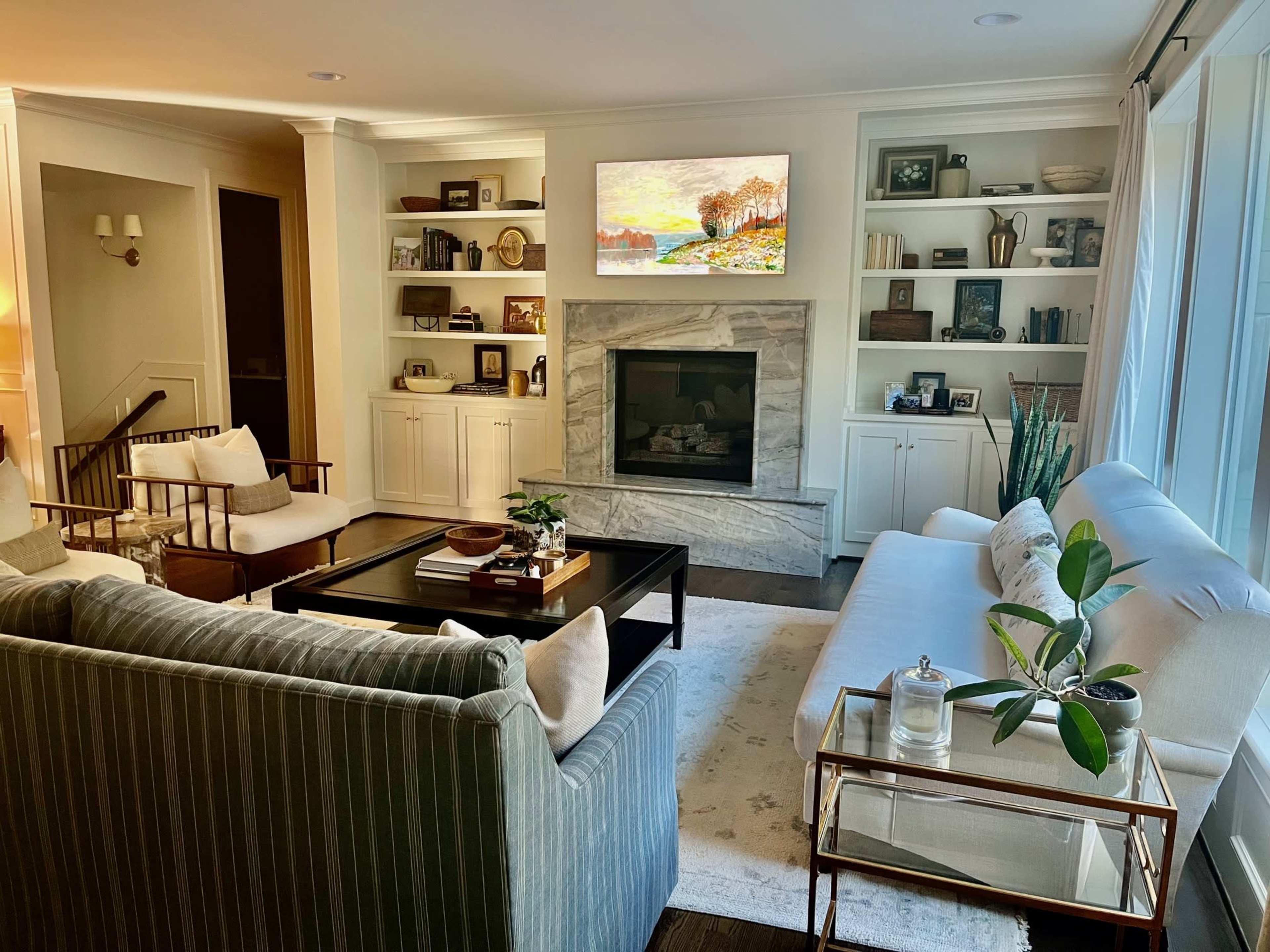 The image shows a modern living room with a fireplace, bookshelves, and two sofas arranged around a coffee table.