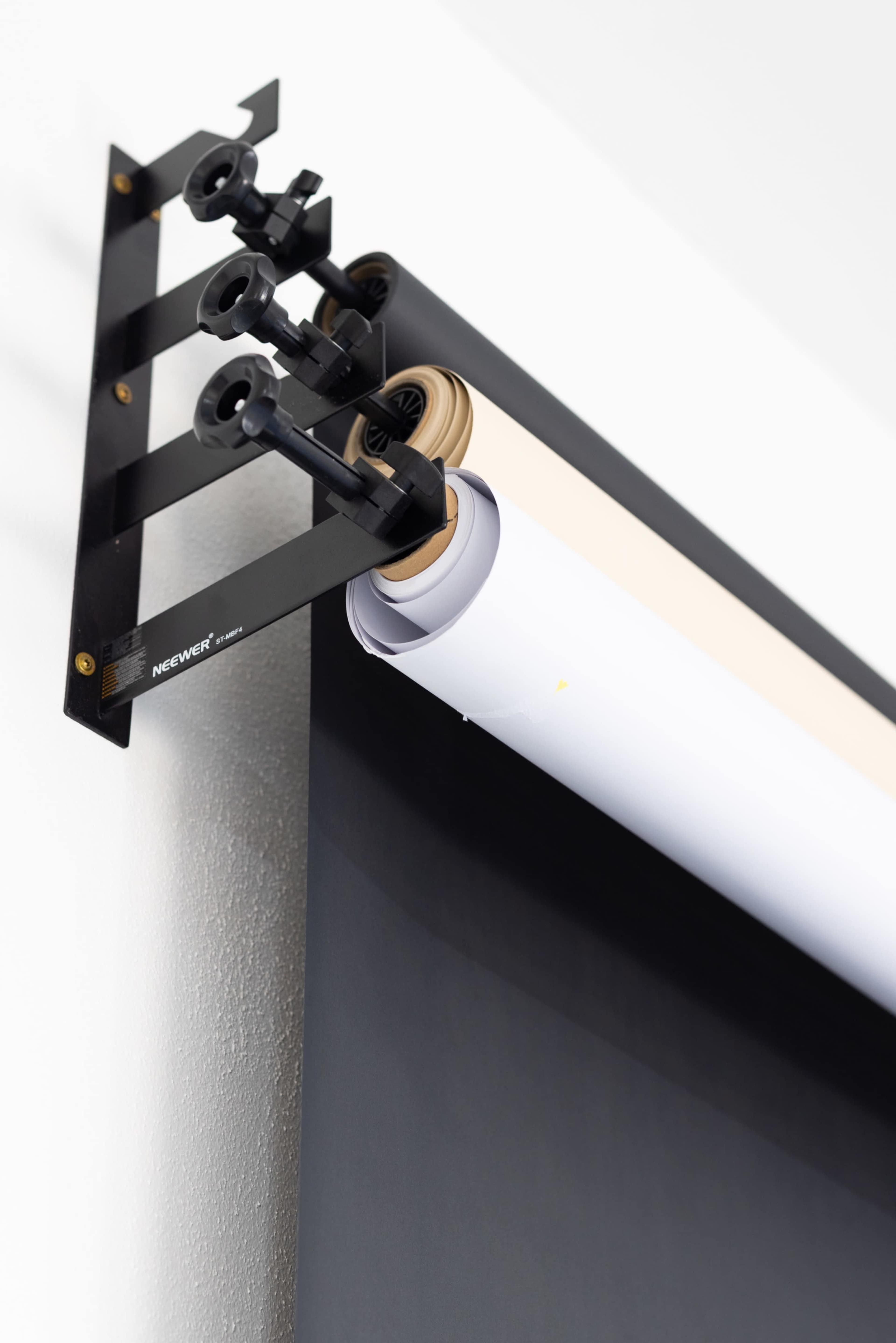 The image shows a wall-mounted paper roll holder with multiple rolls of paper, including a white and a brown roll, ready for use.