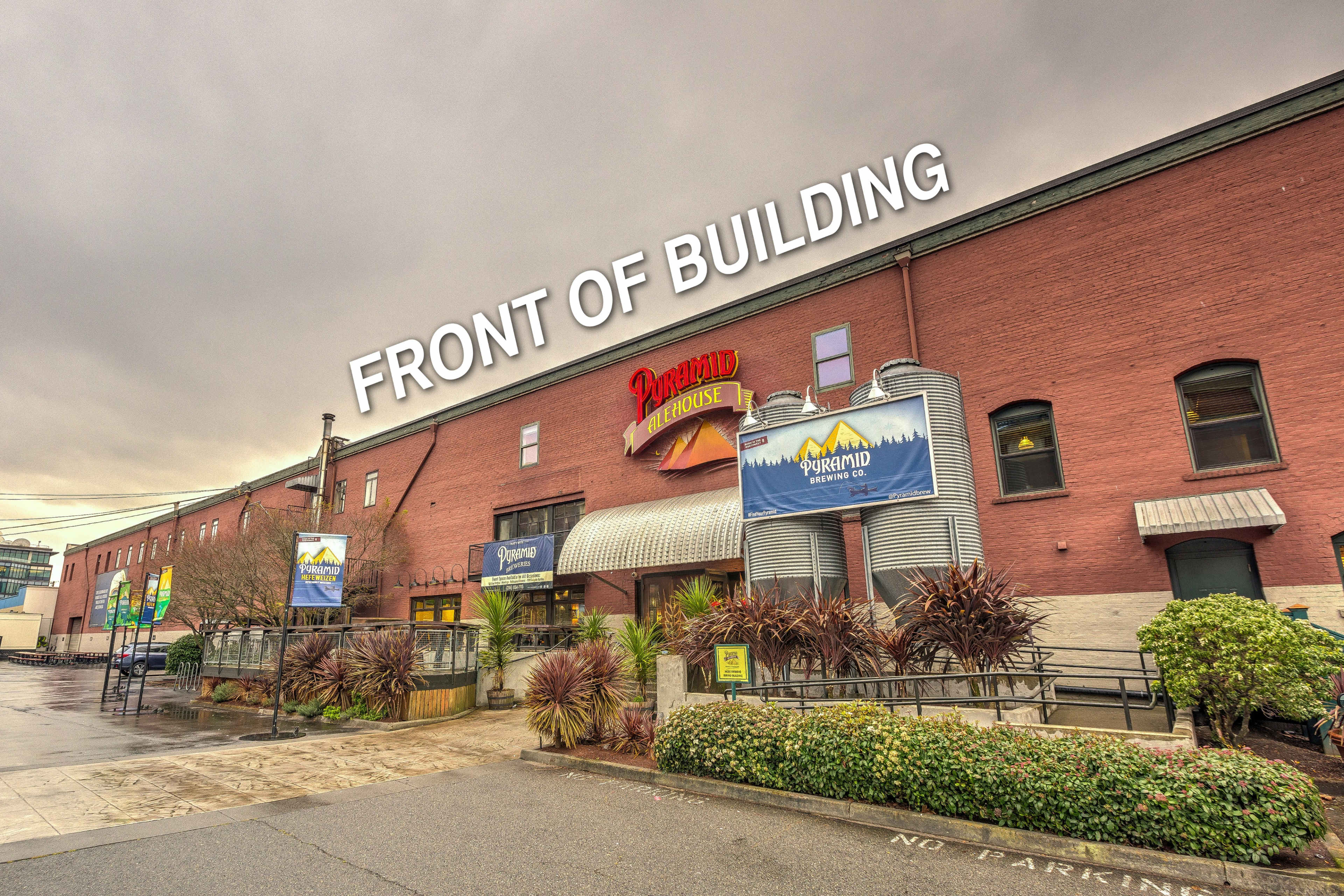 The front exterior of a large brick building with signage and landscaping.