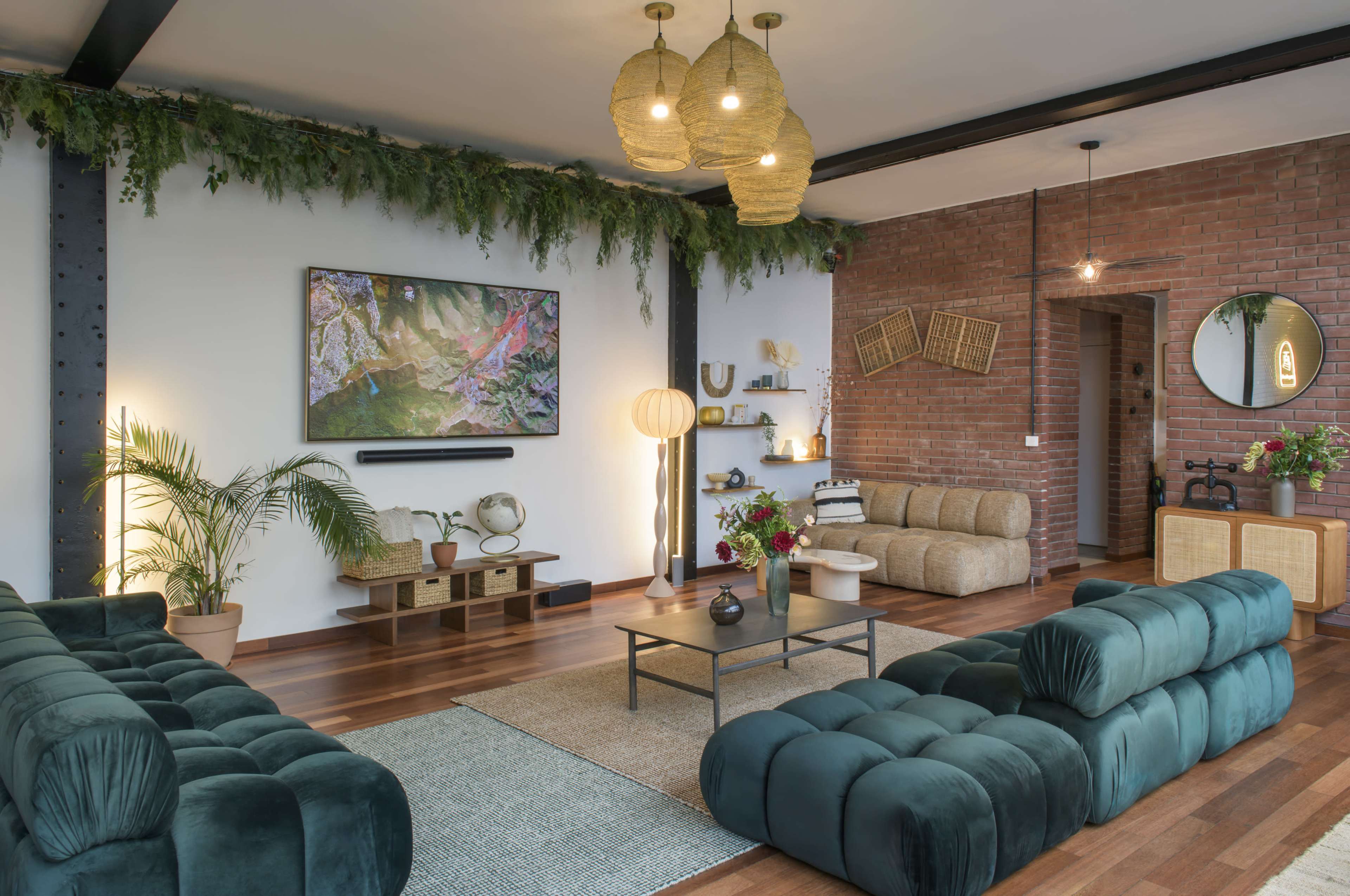 The image showcases a modern living room with teal sofas, a coffee table, a brick wall, and decorative plants.