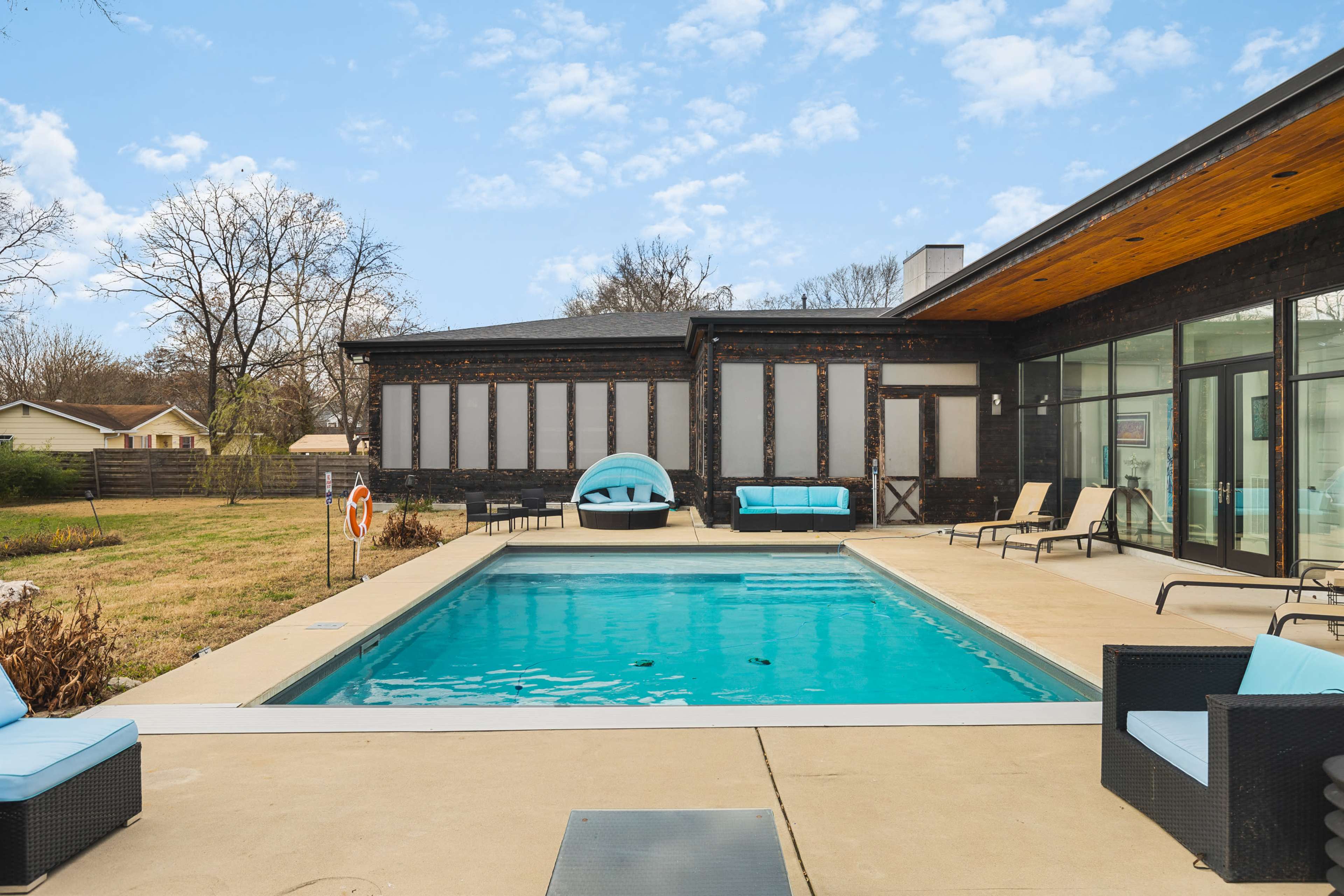 A swimming pool surrounded by lounge chairs and a house with a modern design.
