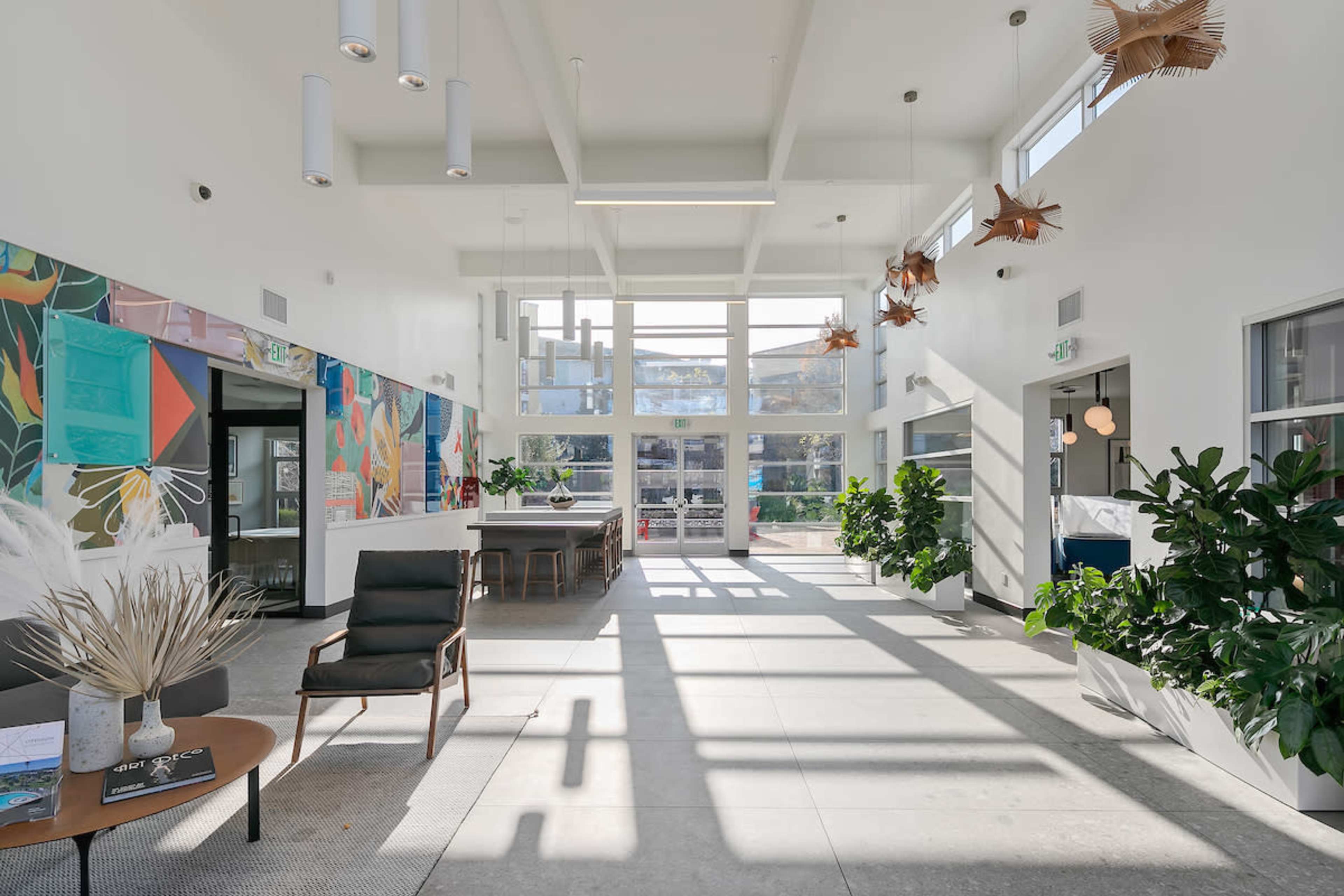 A bright lobby area with large windows, modern furniture, and decorative plants.
