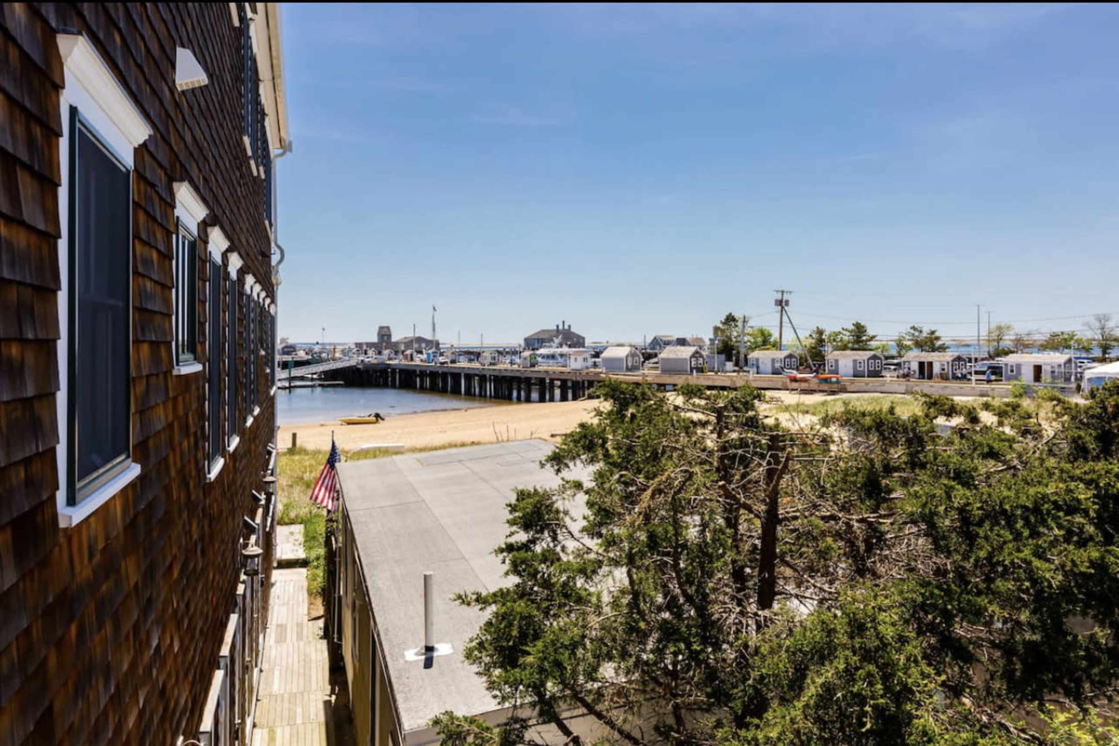 A view from a building showing a pier extending into the water with parked trailers and beach sand in the background.