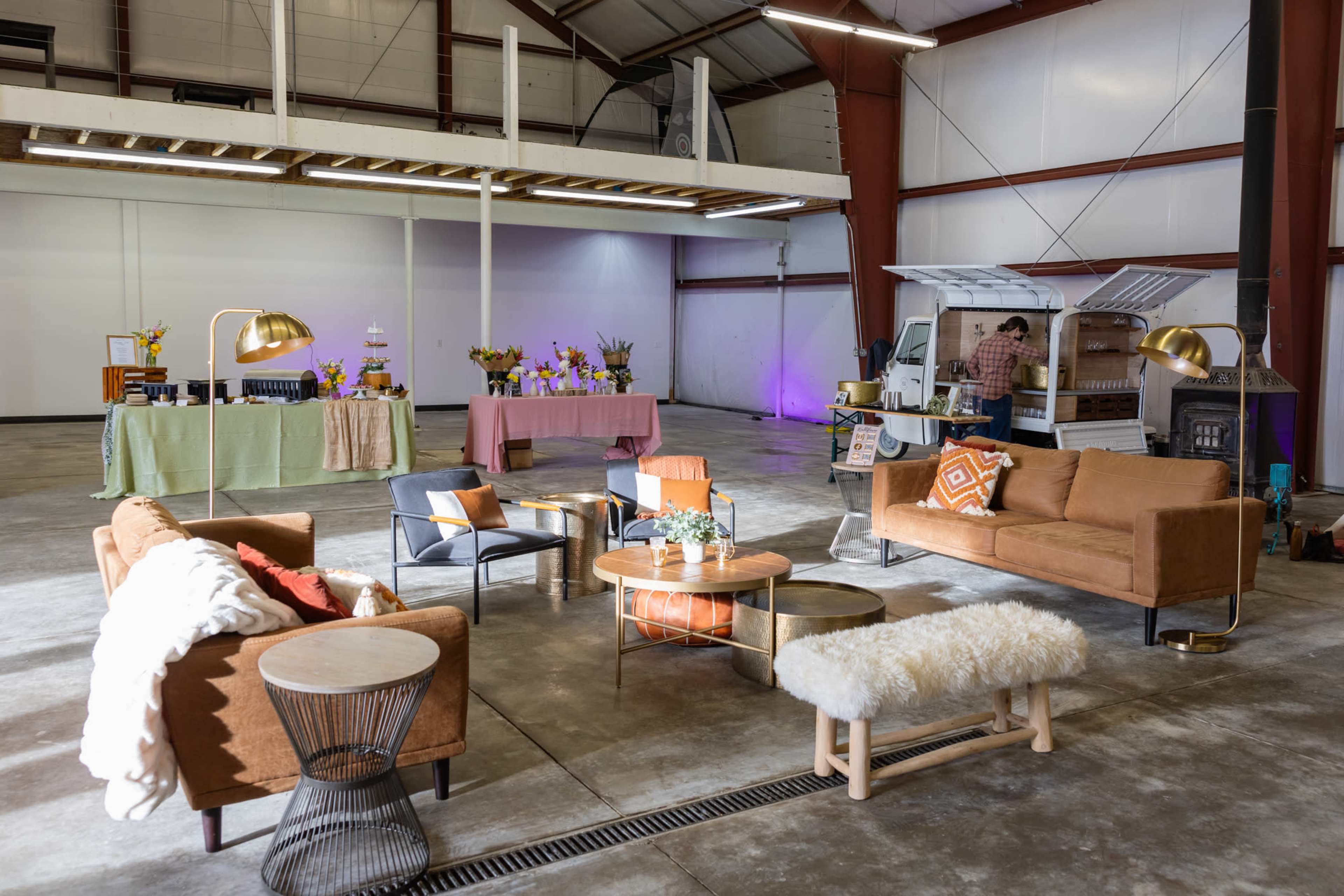 A spacious interior with various seating arrangements, tables adorned with floral arrangements, and a service area in the background.