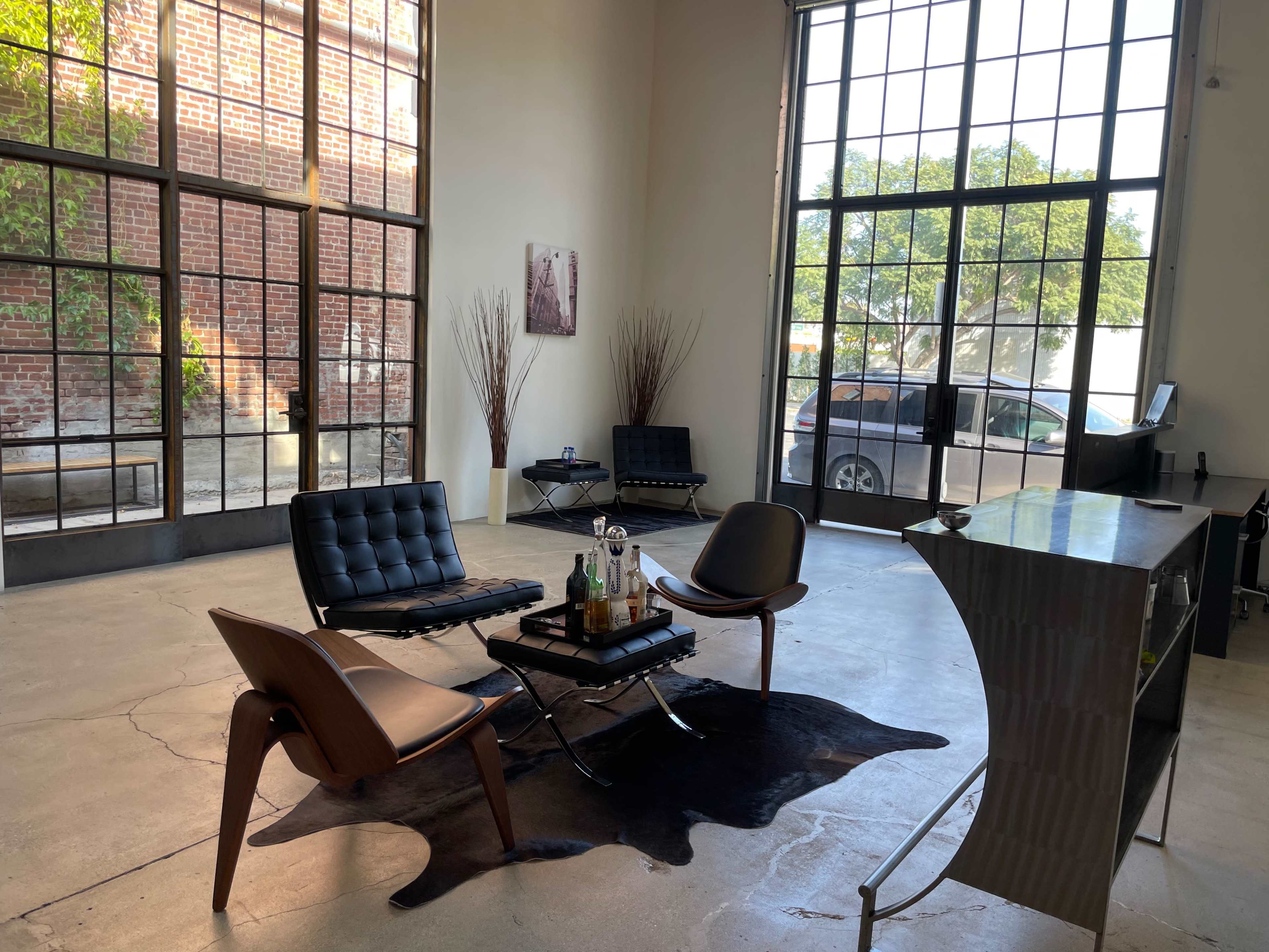 A spacious interior features modern seating and a bar area, with large windows allowing natural light to fill the room.