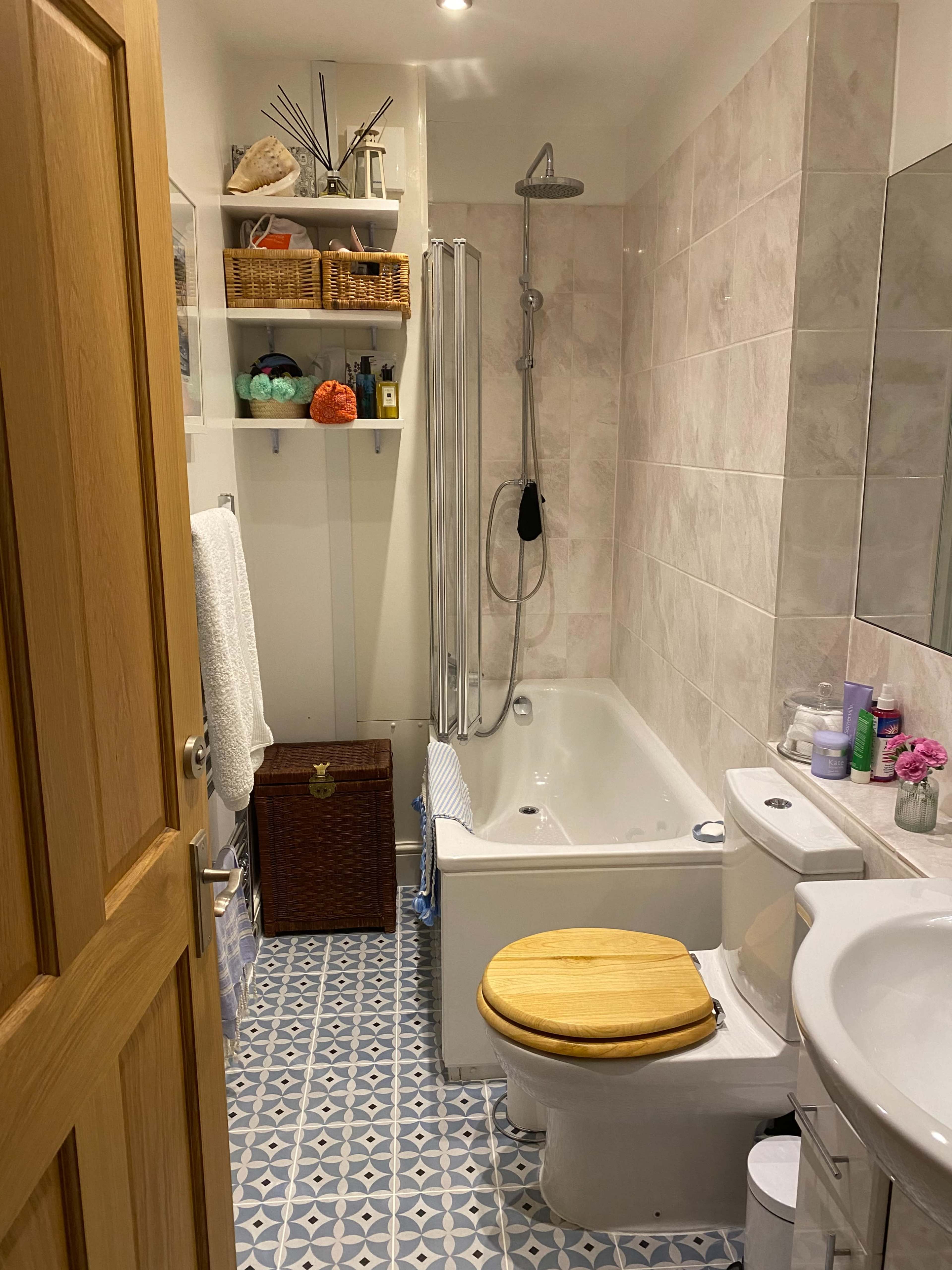 A small bathroom with a bathtub, toilet, sink, and various toiletries on display.