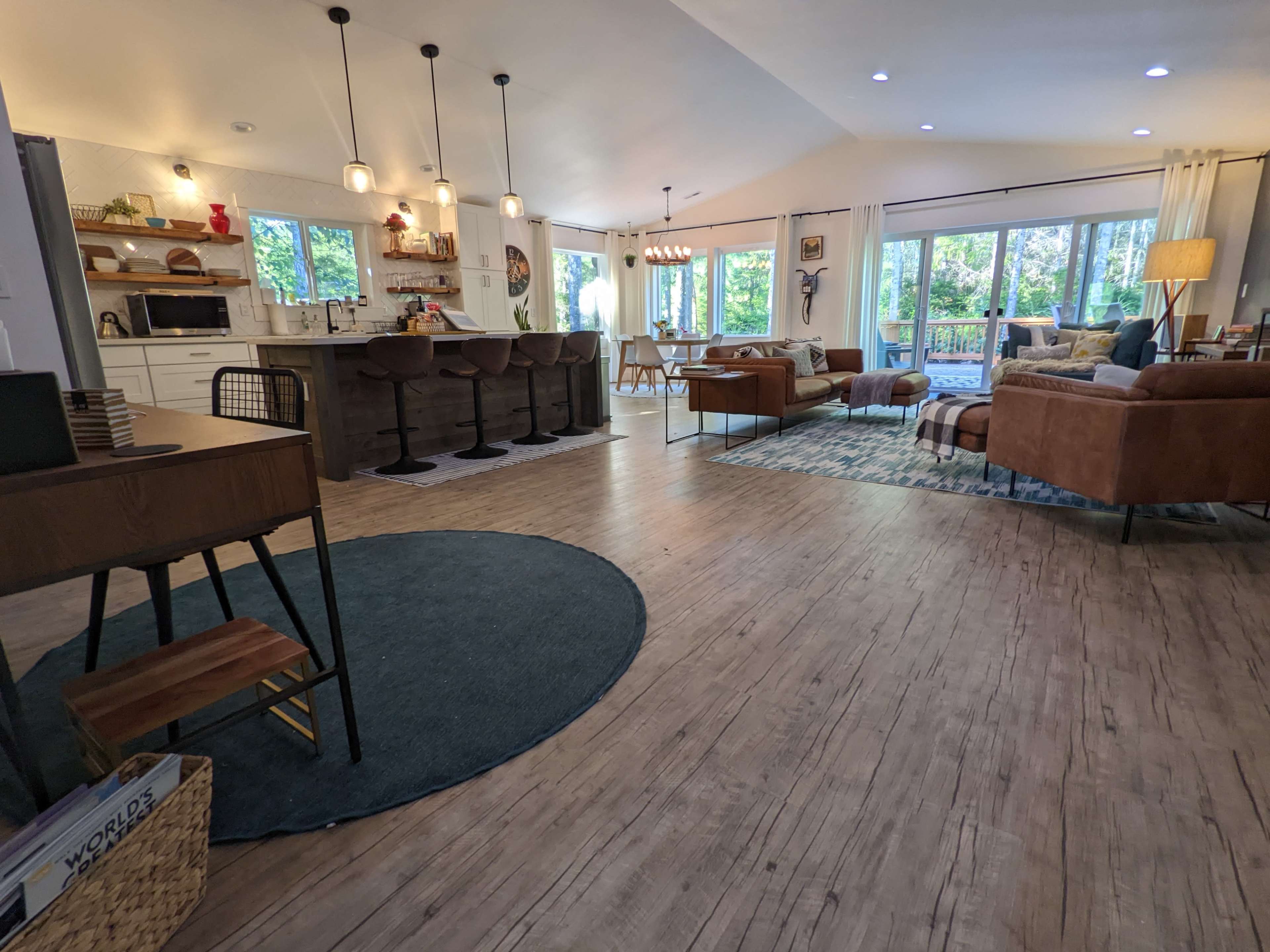 A spacious, open-concept living area with a kitchen, seating arrangements, and large windows that allow natural light.