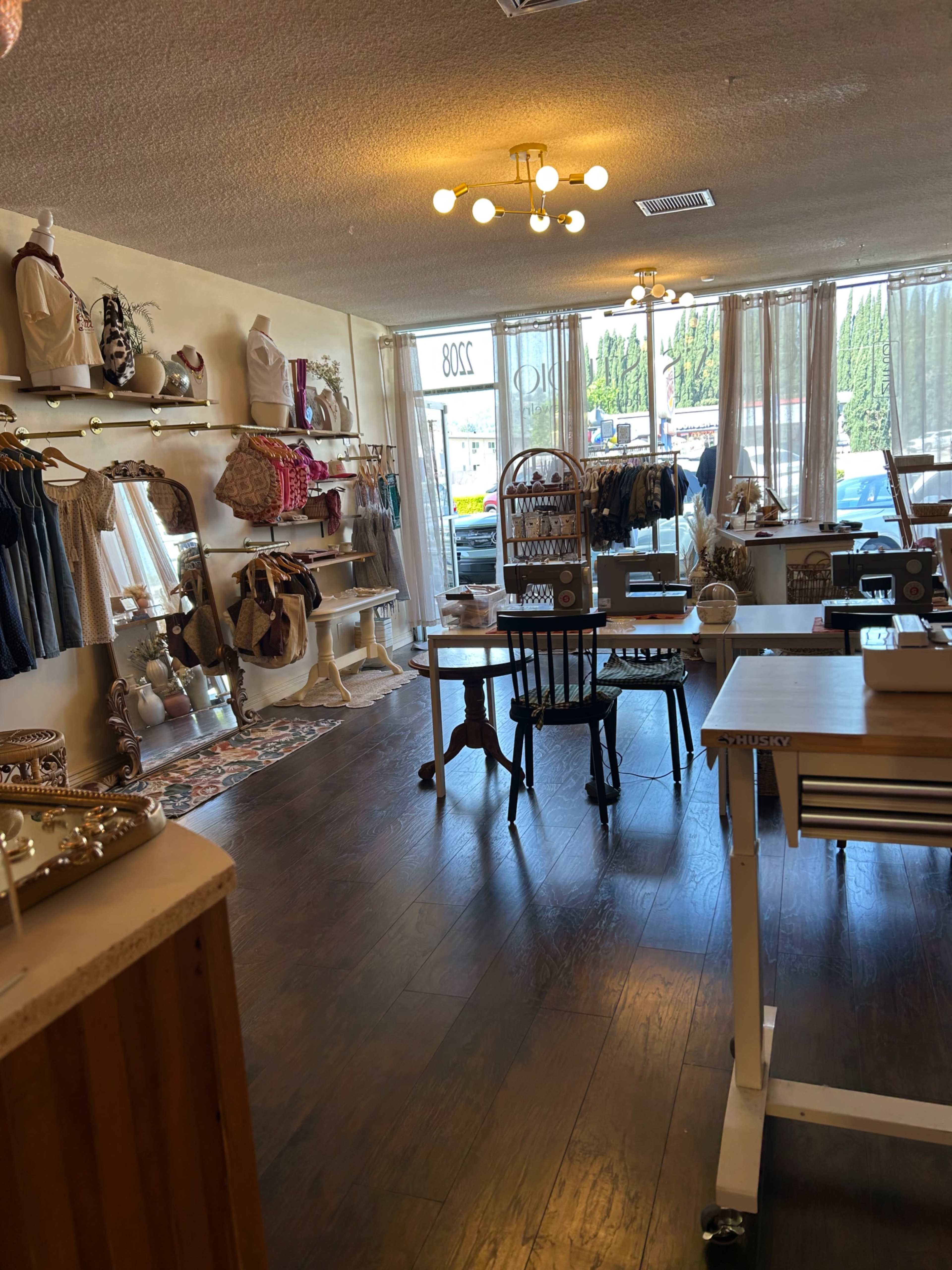 The interior of a boutique features clothing racks, shelves with accessories, and a display table under soft lighting.