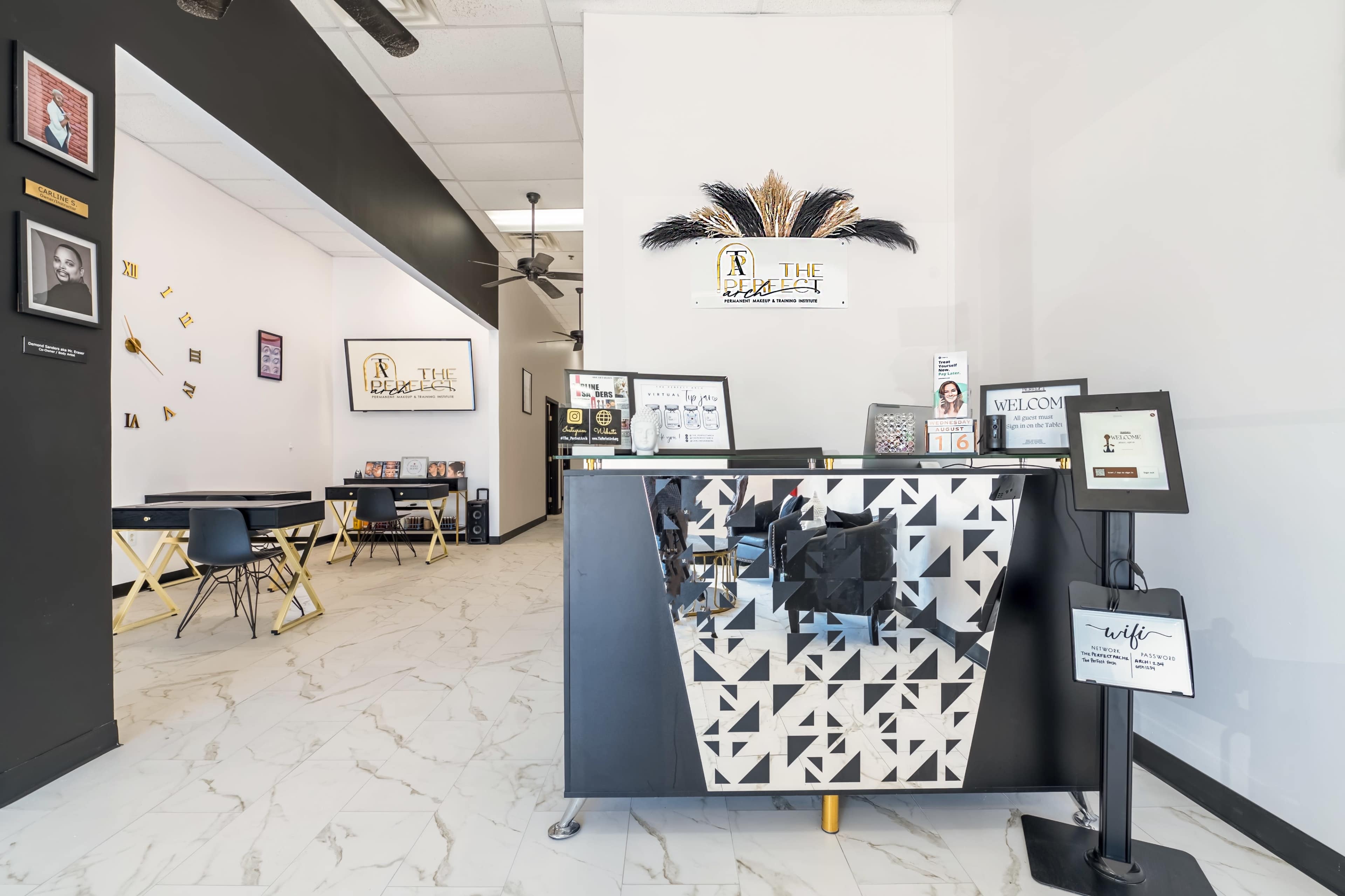 The image shows a modern reception area with a mirrored front desk and a black-and-white color scheme, featuring seating and decorative wall art.