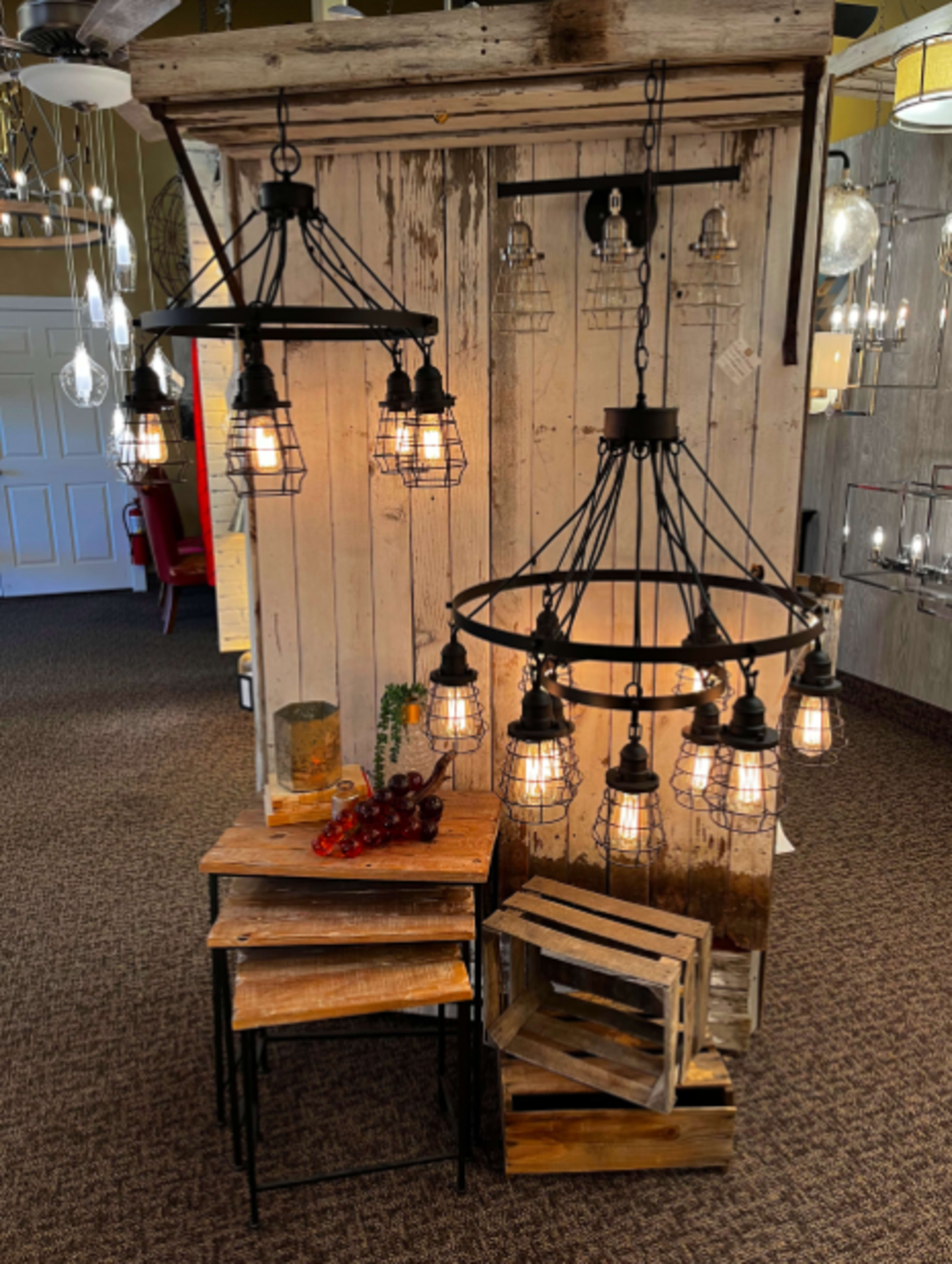 A display of various hanging light fixtures arranged around stacked wooden crates and tables in a store setting.