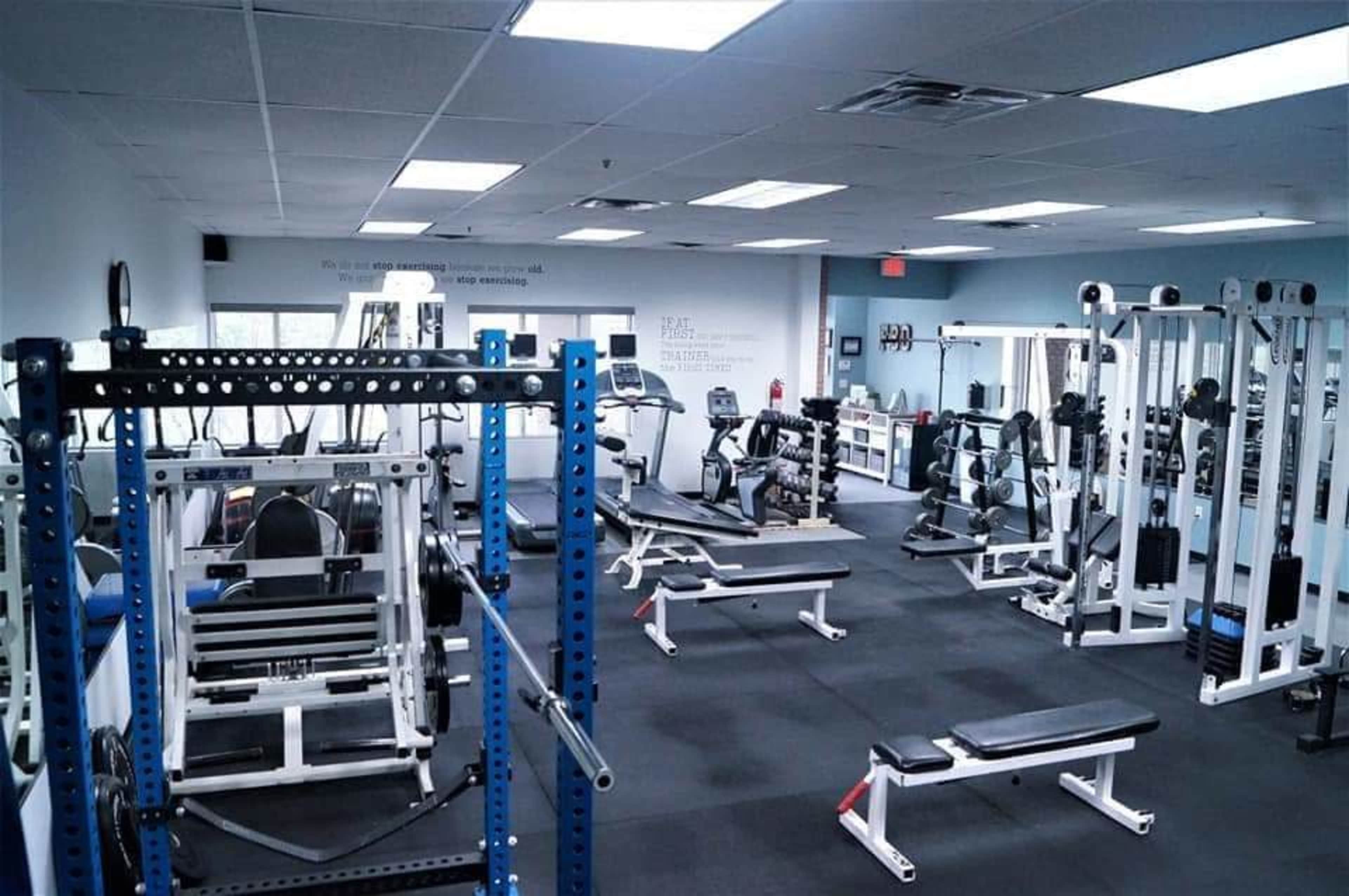 A gym interior filled with various weightlifting and cardio equipment arranged in a spacious layout.