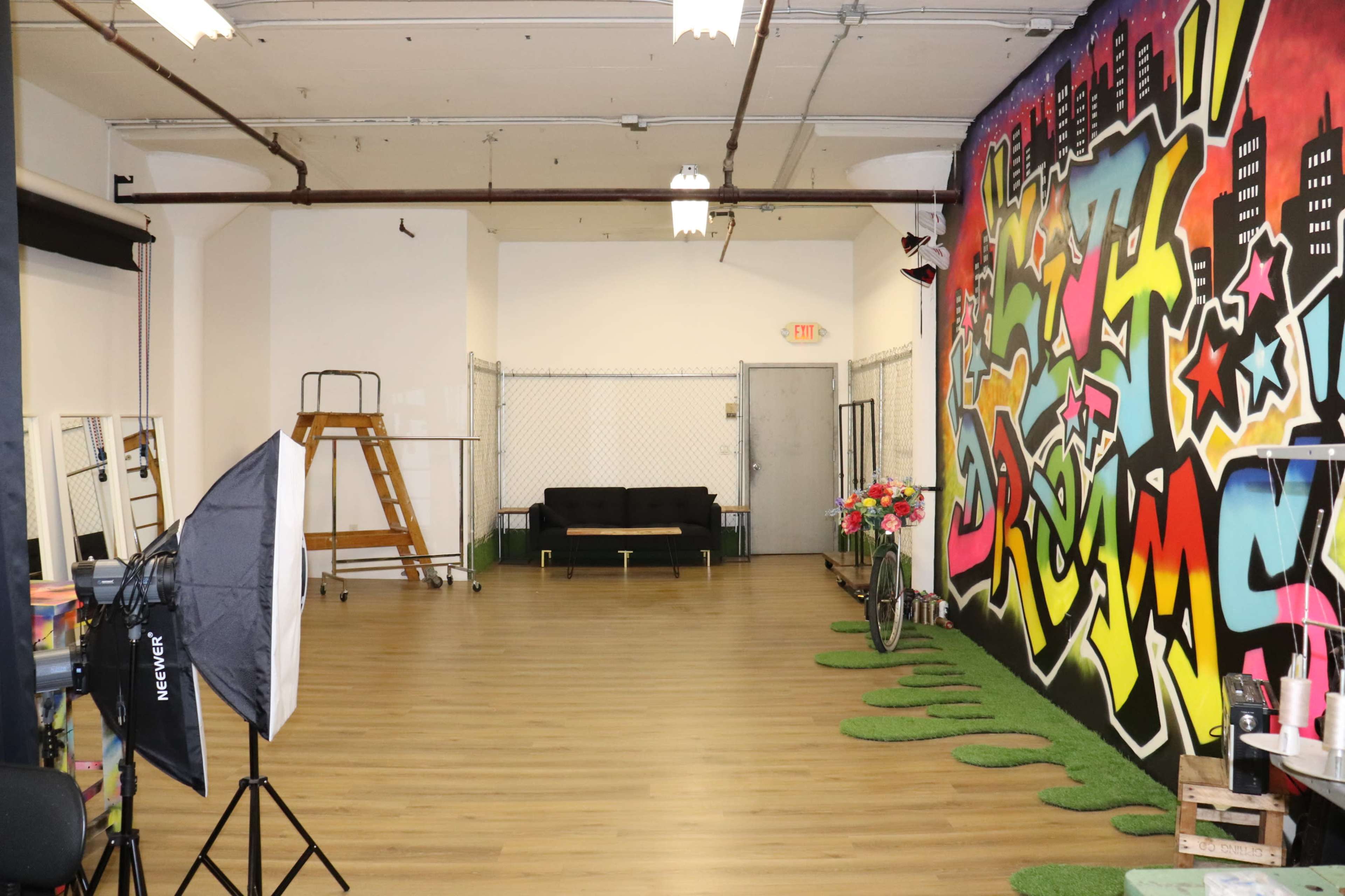 A spacious indoor area featuring a vibrant graffiti wall, a sofa, and green decorative grass patches on the floor.