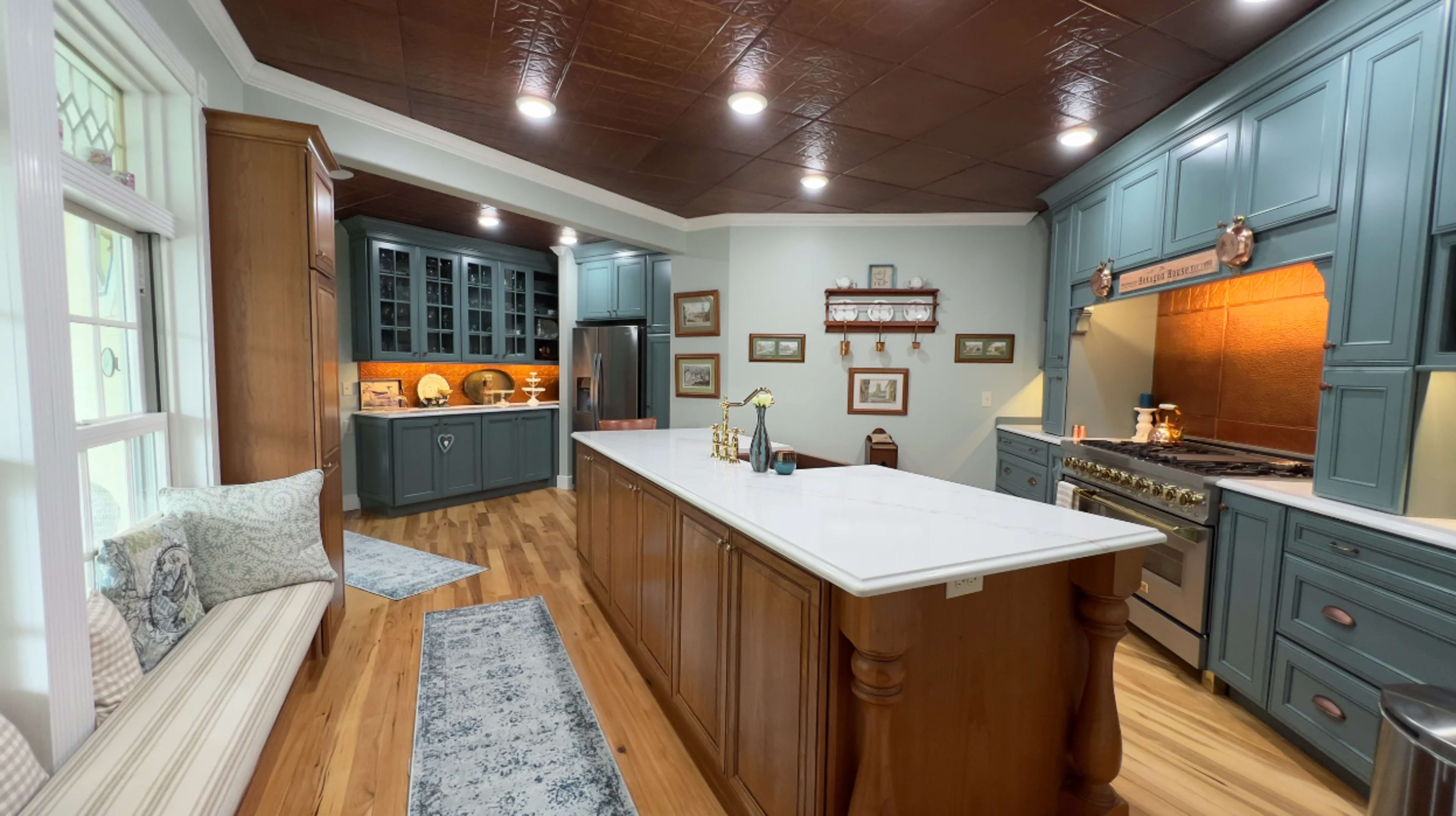 A spacious kitchen featuring blue cabinetry, a large island with a white countertop, and wooden flooring.