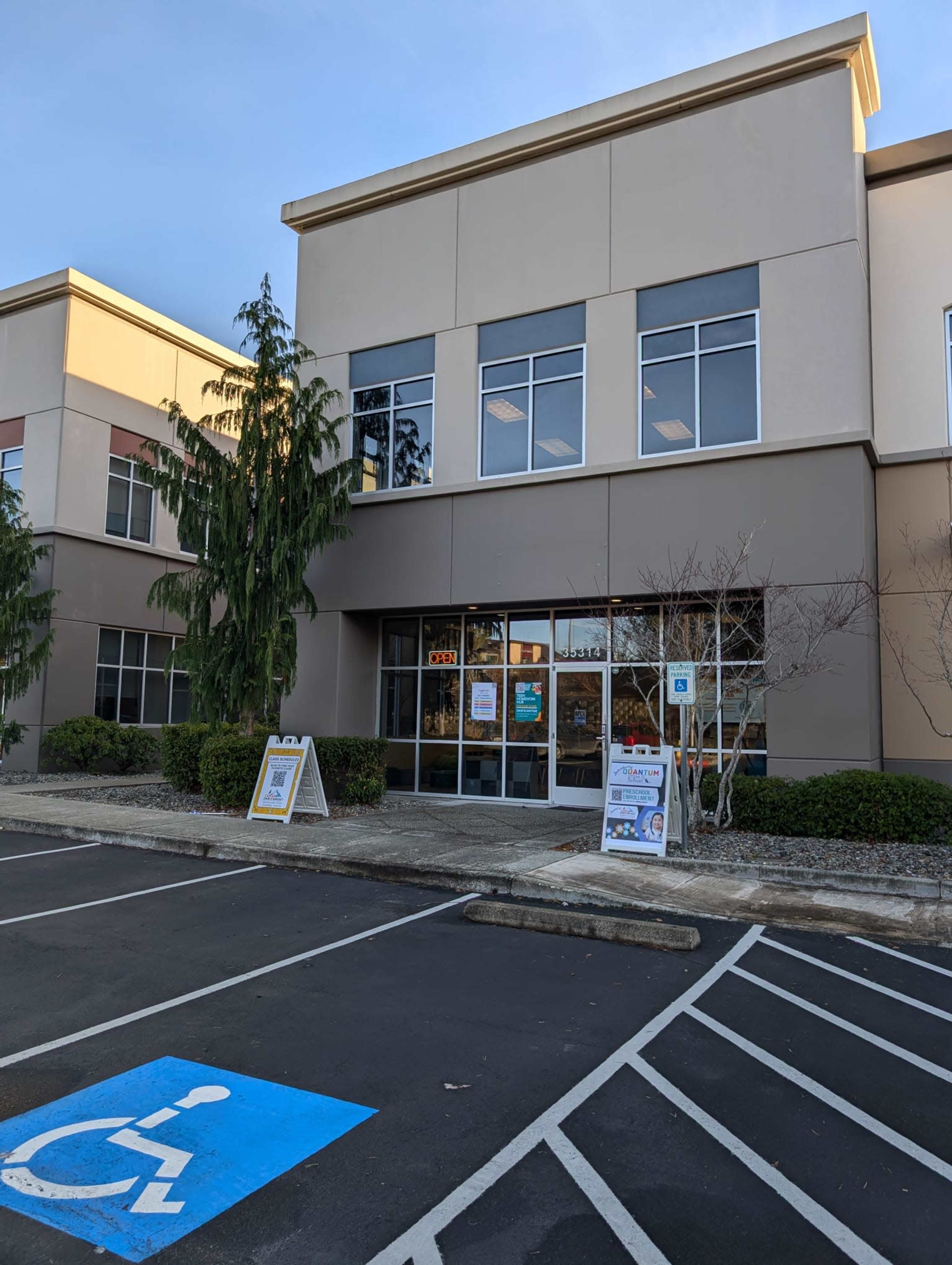 The image shows a commercial building with large windows and an accessible parking space marked in front.