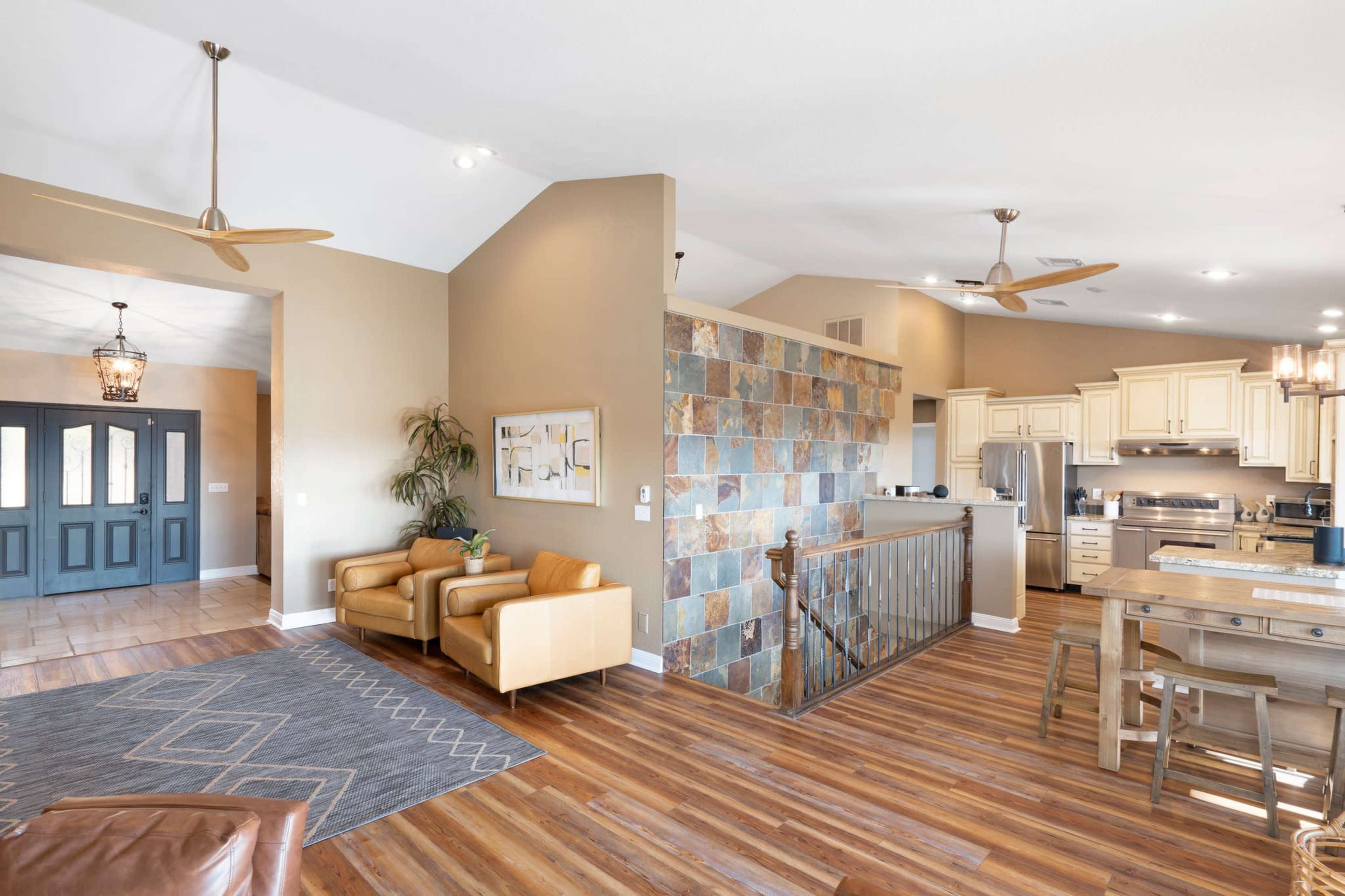 A spacious living area featuring a kitchen, dining table, and a cozy seating space with a stone wall accent.