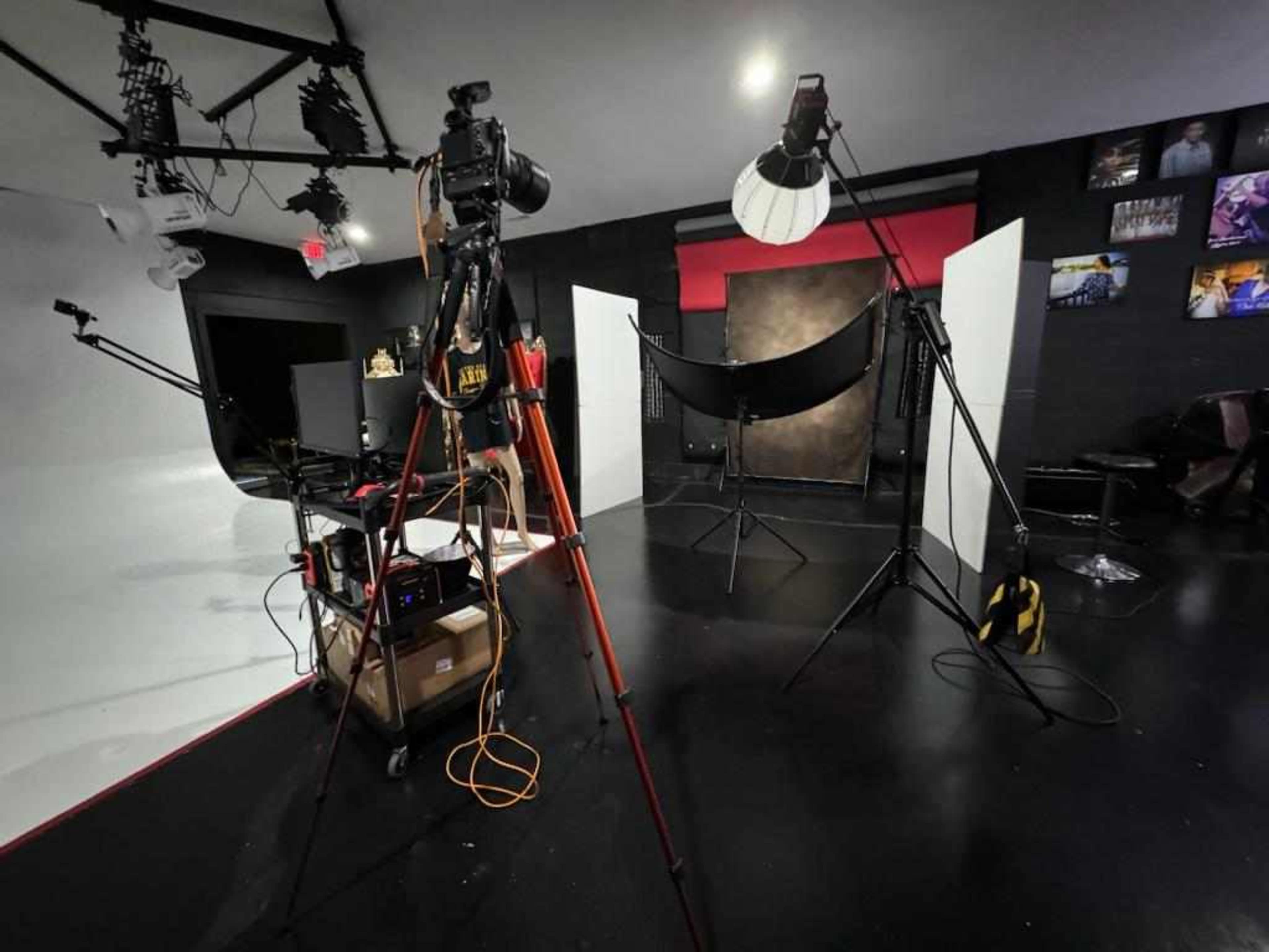 A photography studio features multiple camera setup and lighting equipment arranged around a backdrop.