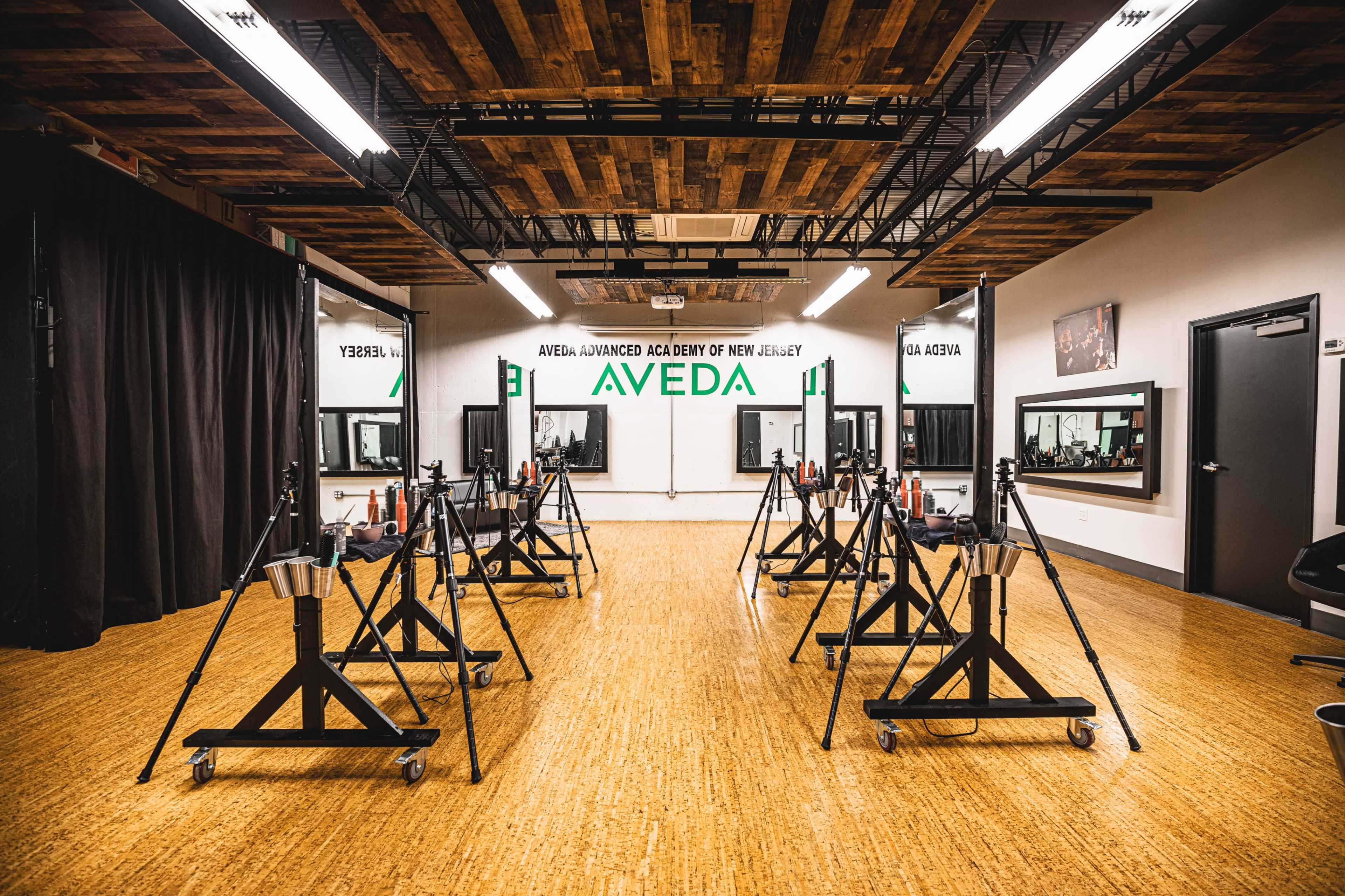 A spacious salon setup with several mobile styling stations arranged neatly on a wooden floor, illuminated by bright overhead lights.
