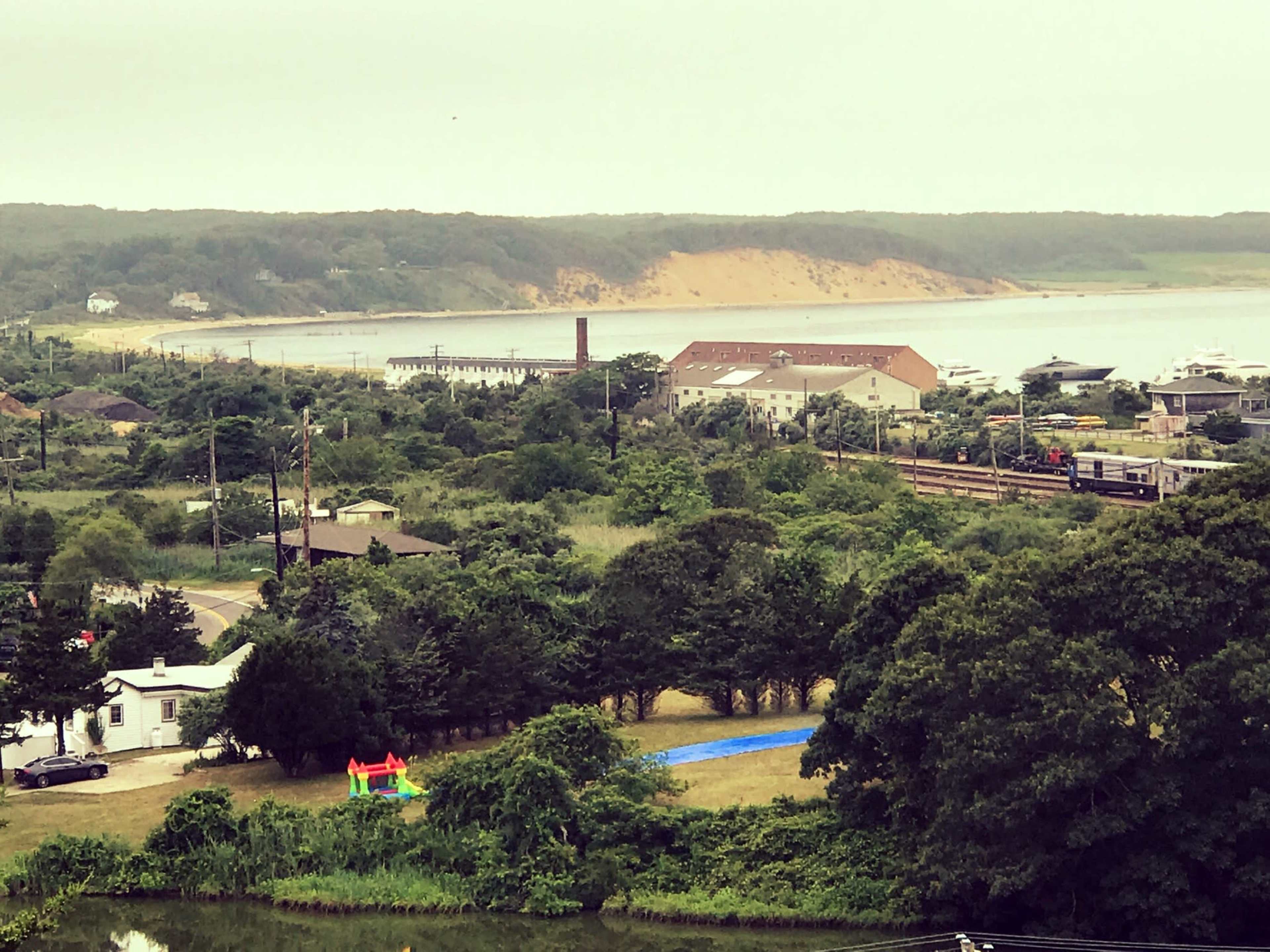 A coastal landscape featuring a small town with a playground and a large sandy hillside in the background.