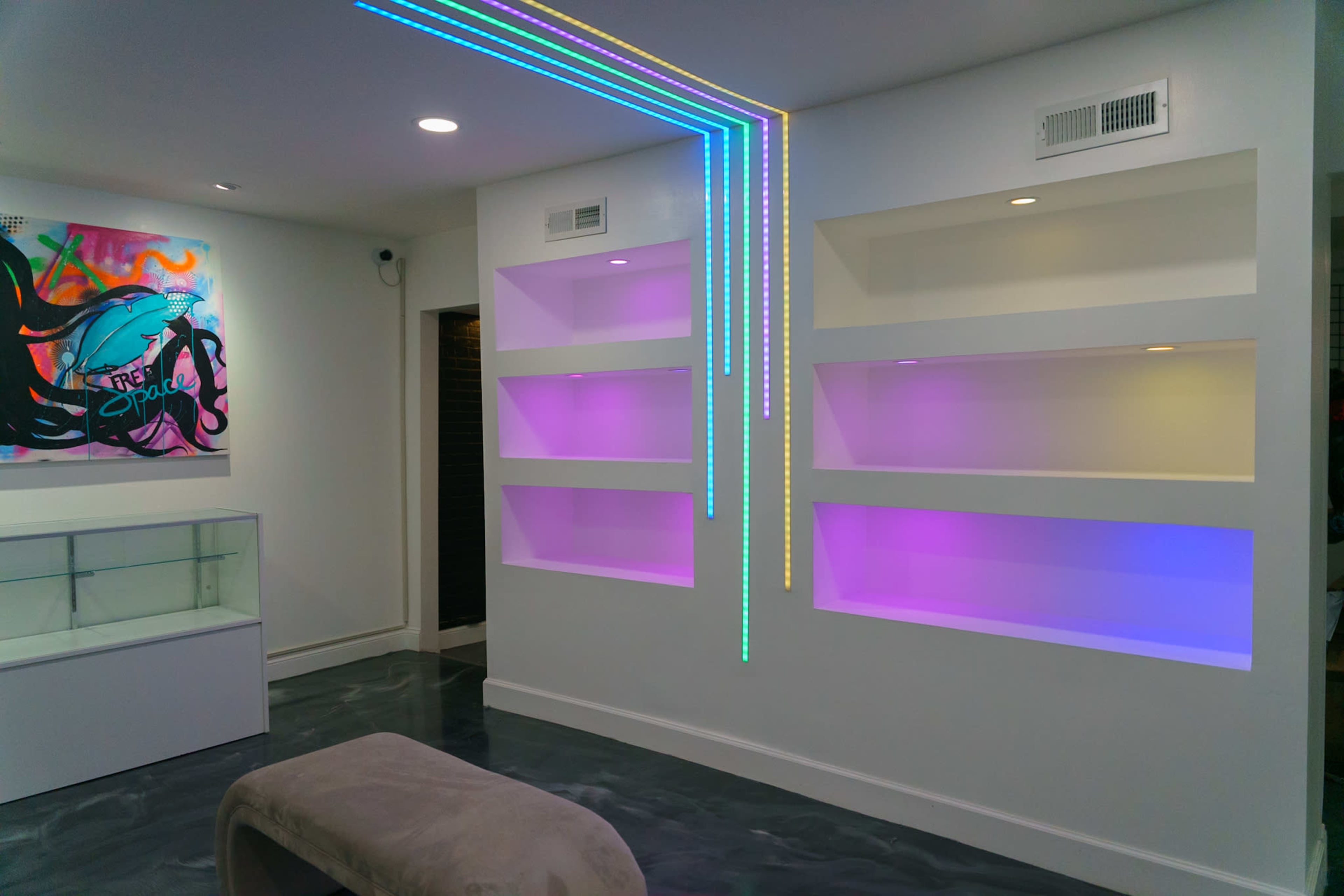 A modern interior showcases illuminated shelves and a colorful wall art piece.