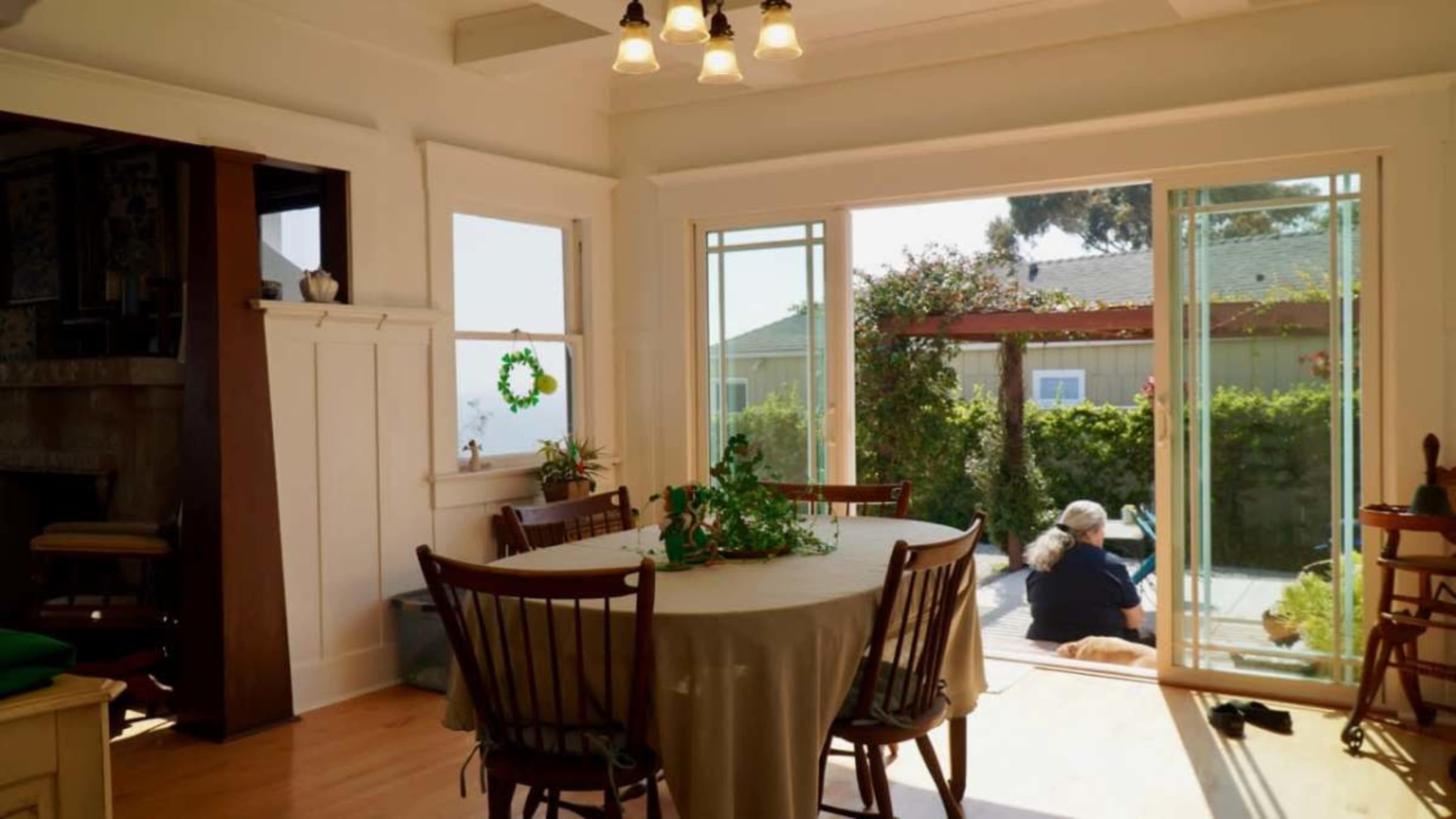 A dining area features a round table with chairs and a view of a patio through sliding glass doors.