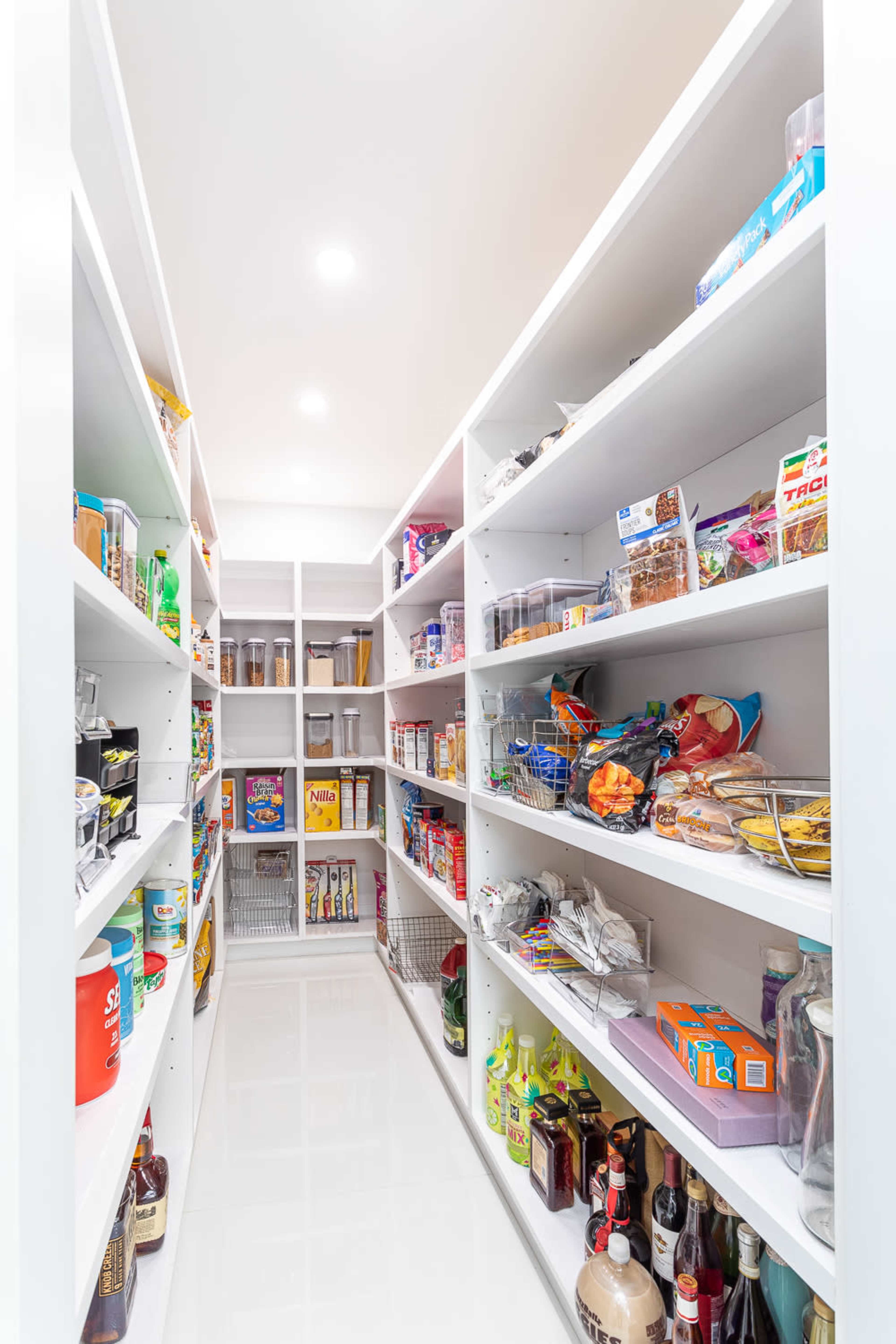 A neatly organized pantry with shelves stocked with various food items and containers on either side.