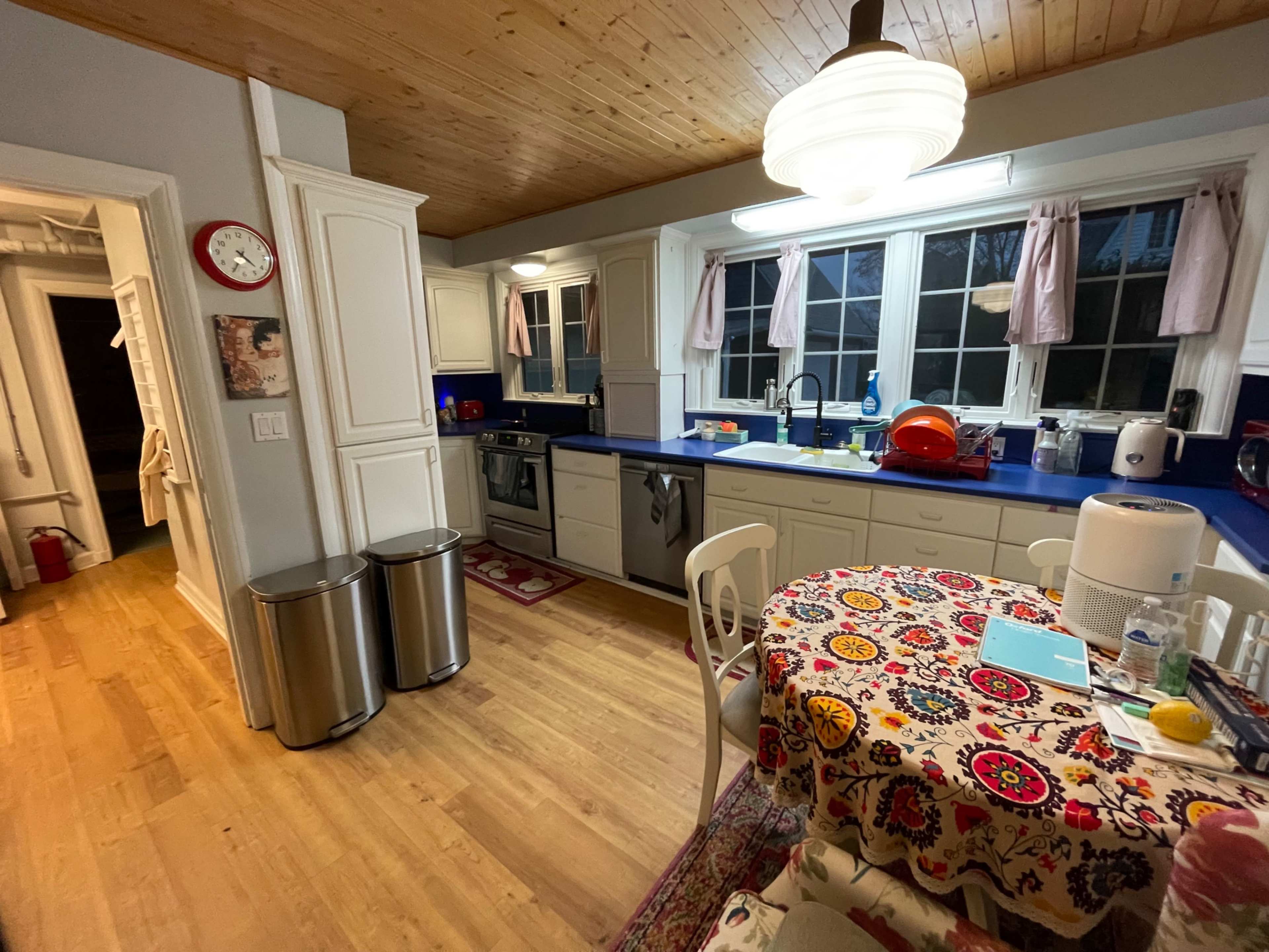 The kitchen features white cabinetry, blue countertops, and a circular table covered with a patterned tablecloth.