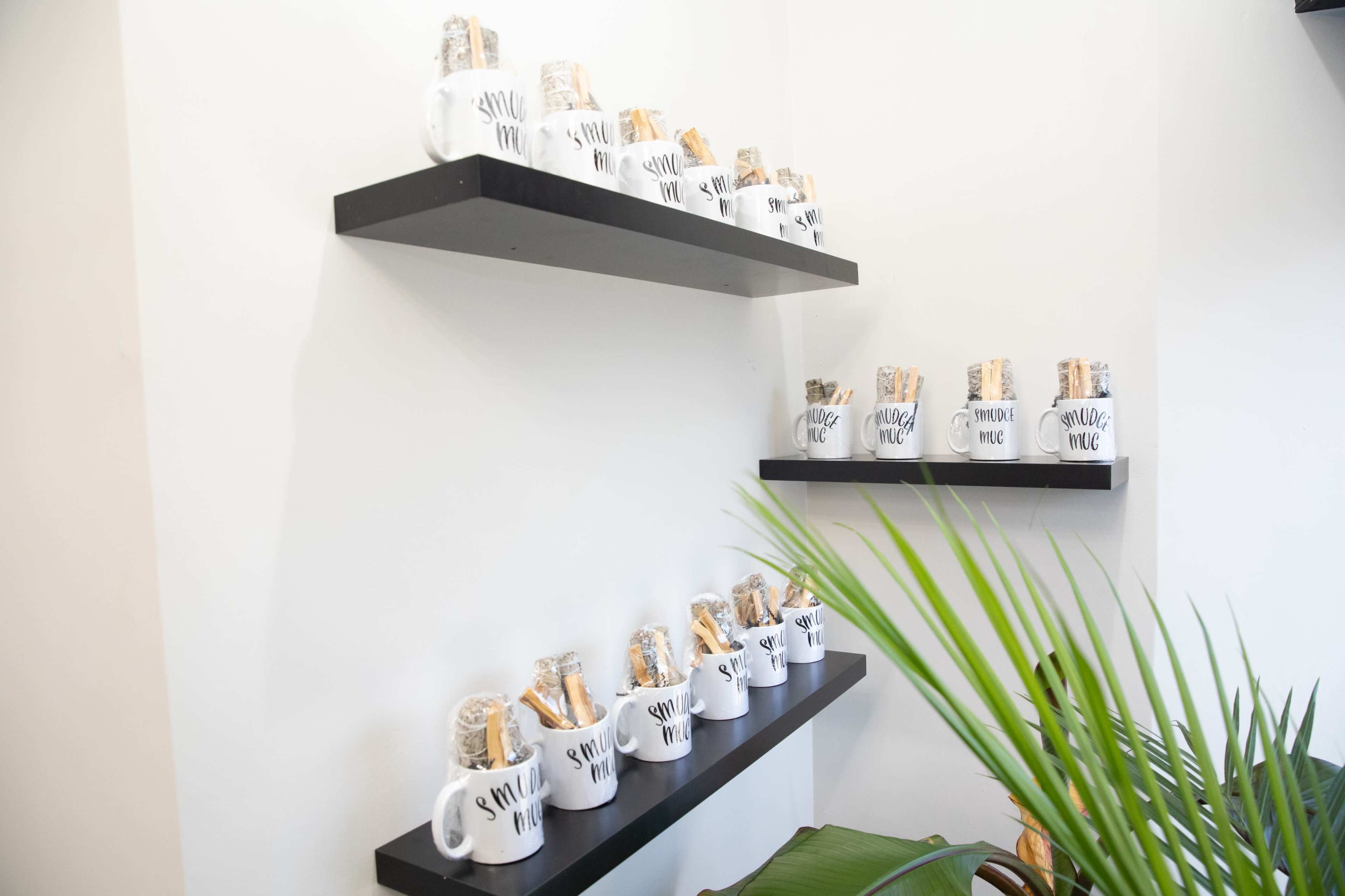 A wall displays several white mugs with text, each filled with snacks and arranged on black shelves.