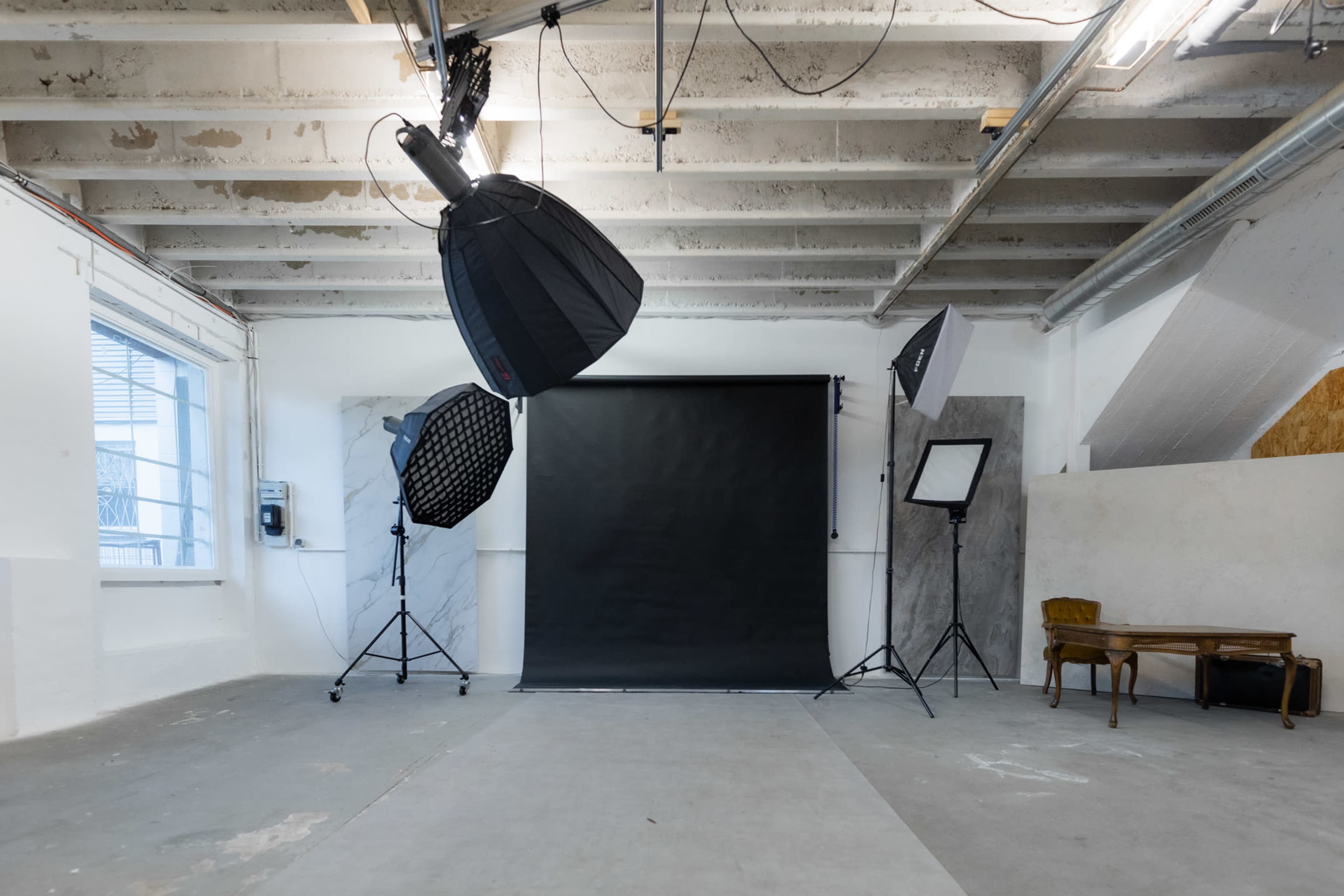 A photography studio equipped with multiple lighting setups and a dark backdrop.