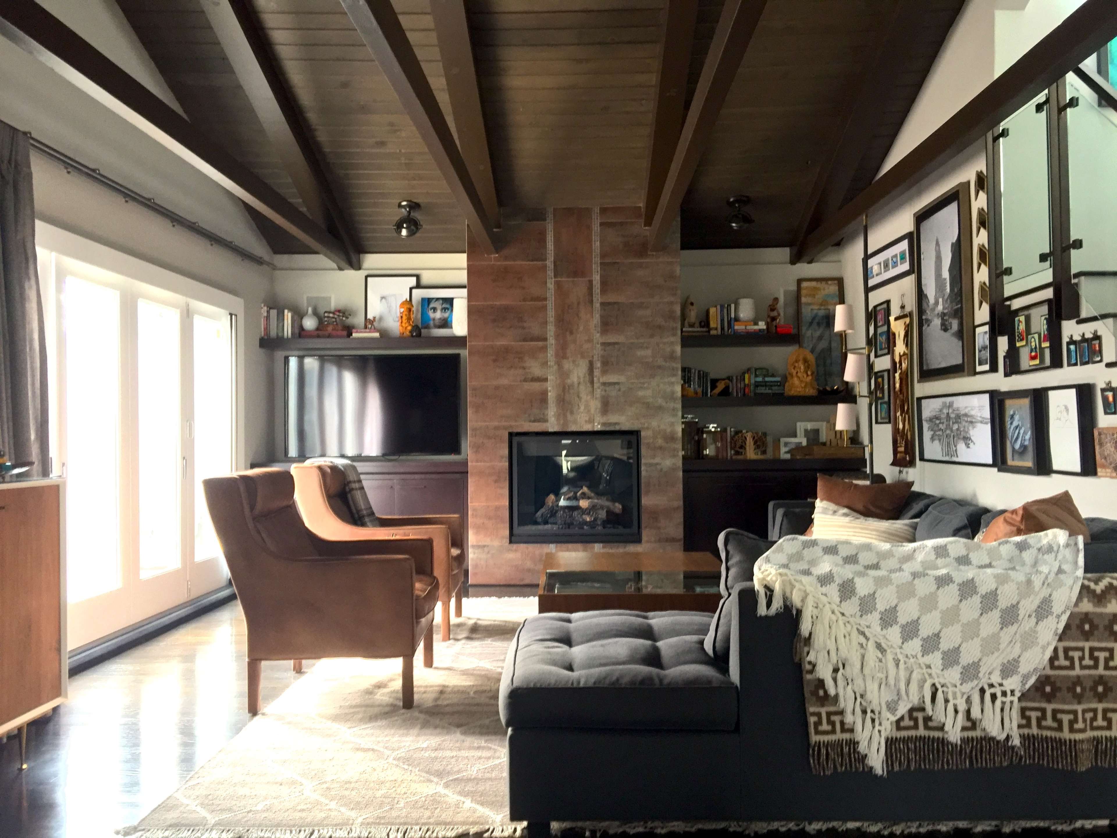 The living room features a sofa and armchairs arranged around a central coffee table, with a fireplace and shelves displaying decor in the background.