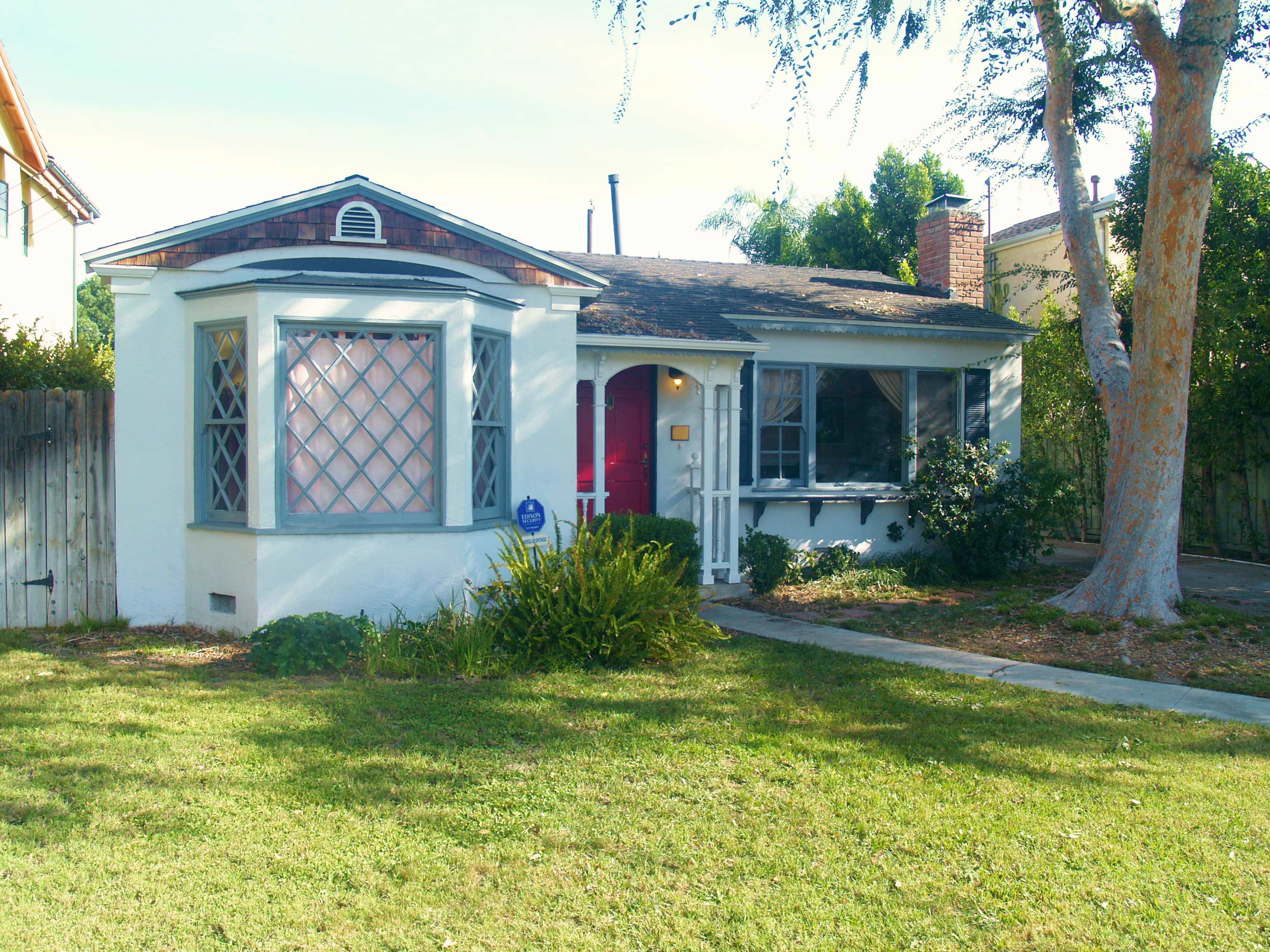 A small, single-story house with a rounded bay window and a well-kept lawn.