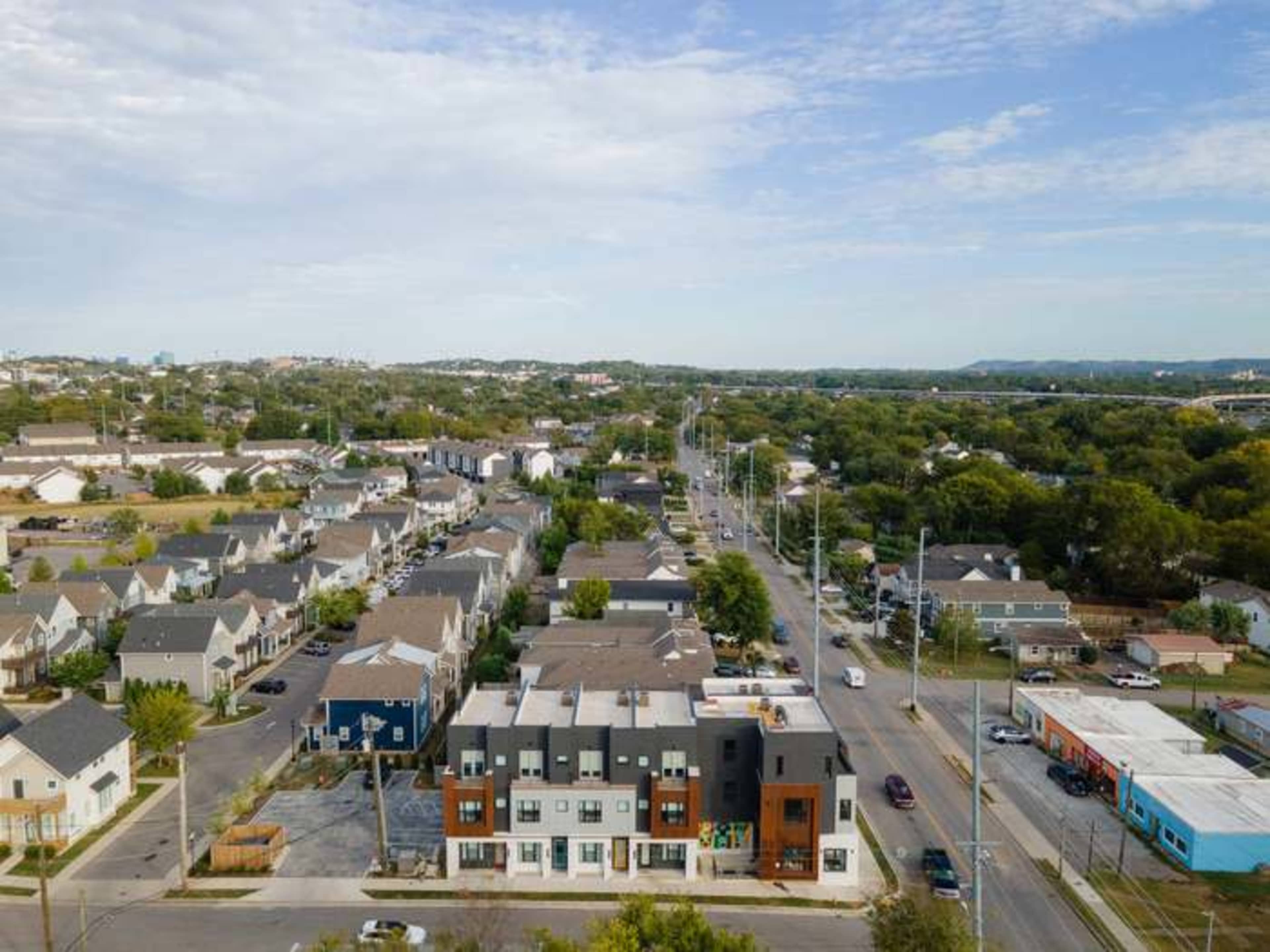 An aerial view shows a mix of residential homes and modern apartment buildings in a suburban neighborhood.