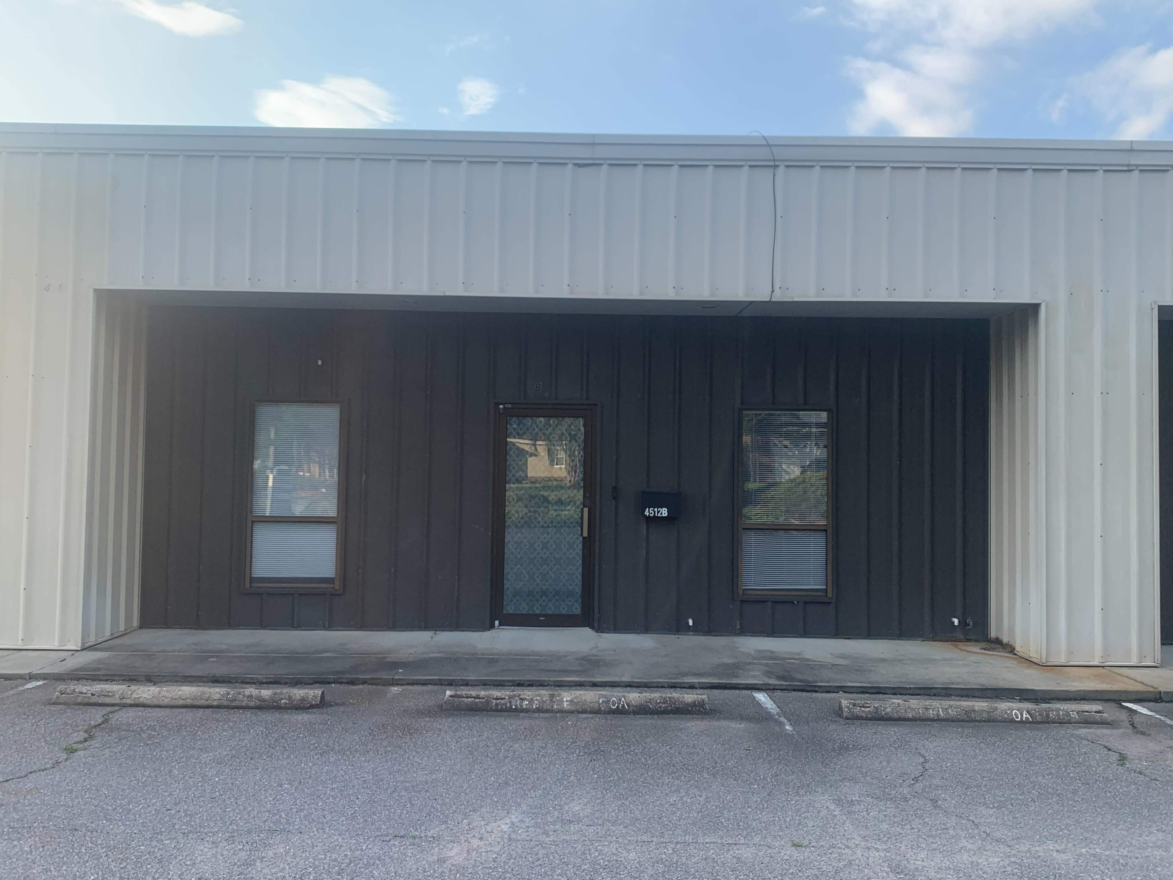 A single-story commercial building with a dark facade and a central entrance flanked by two windows.