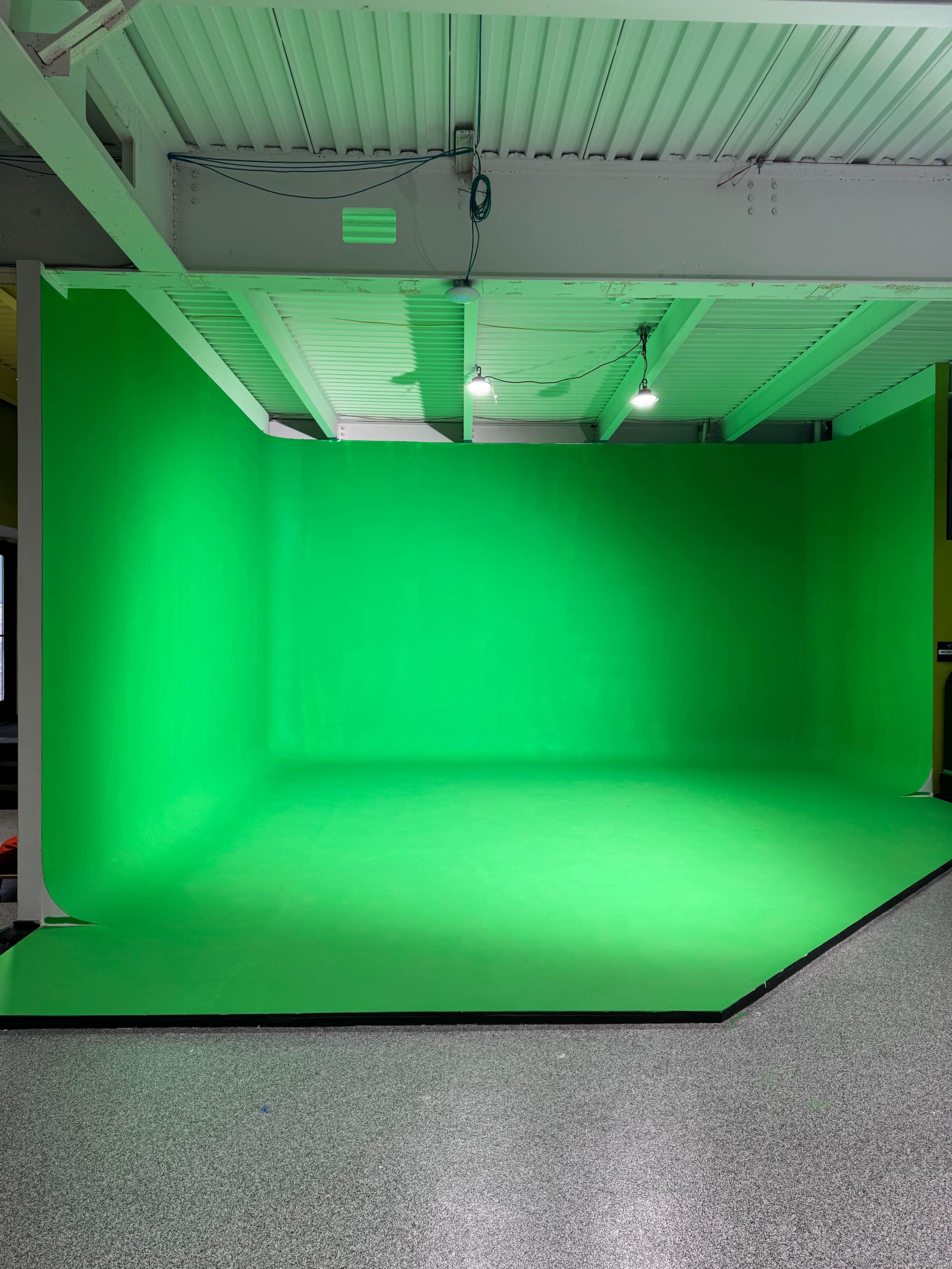 The image shows a brightly lit green screen setup in a room with a textured floor.