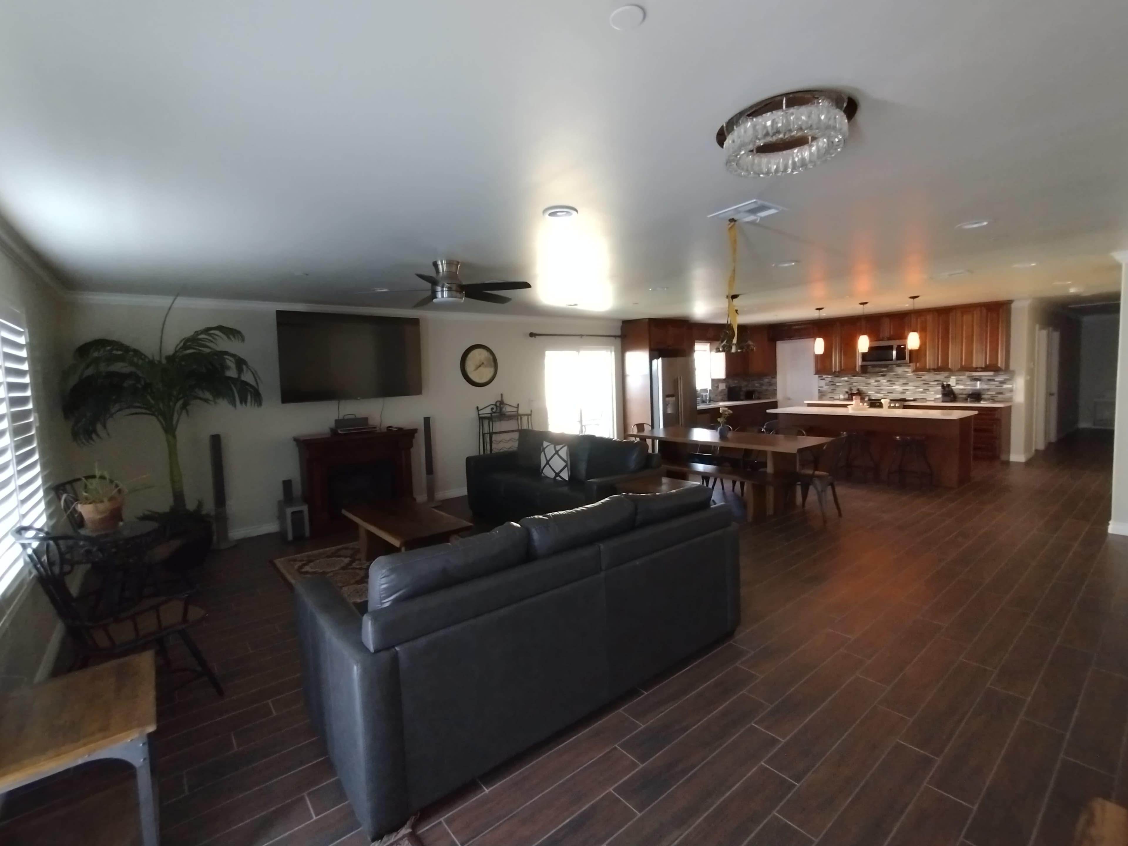 A spacious living area with a seating arrangement, a television, and an open kitchen in the background.