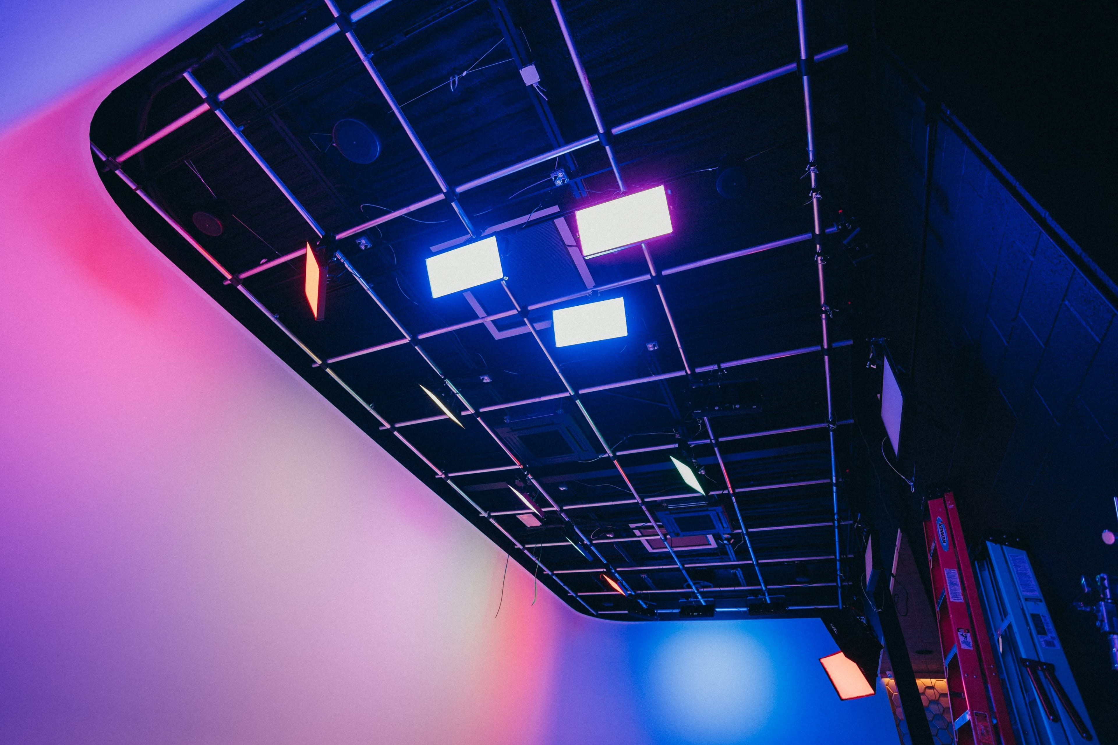 A ceiling with a grid of lights and a smooth wall painted in gradient colors.