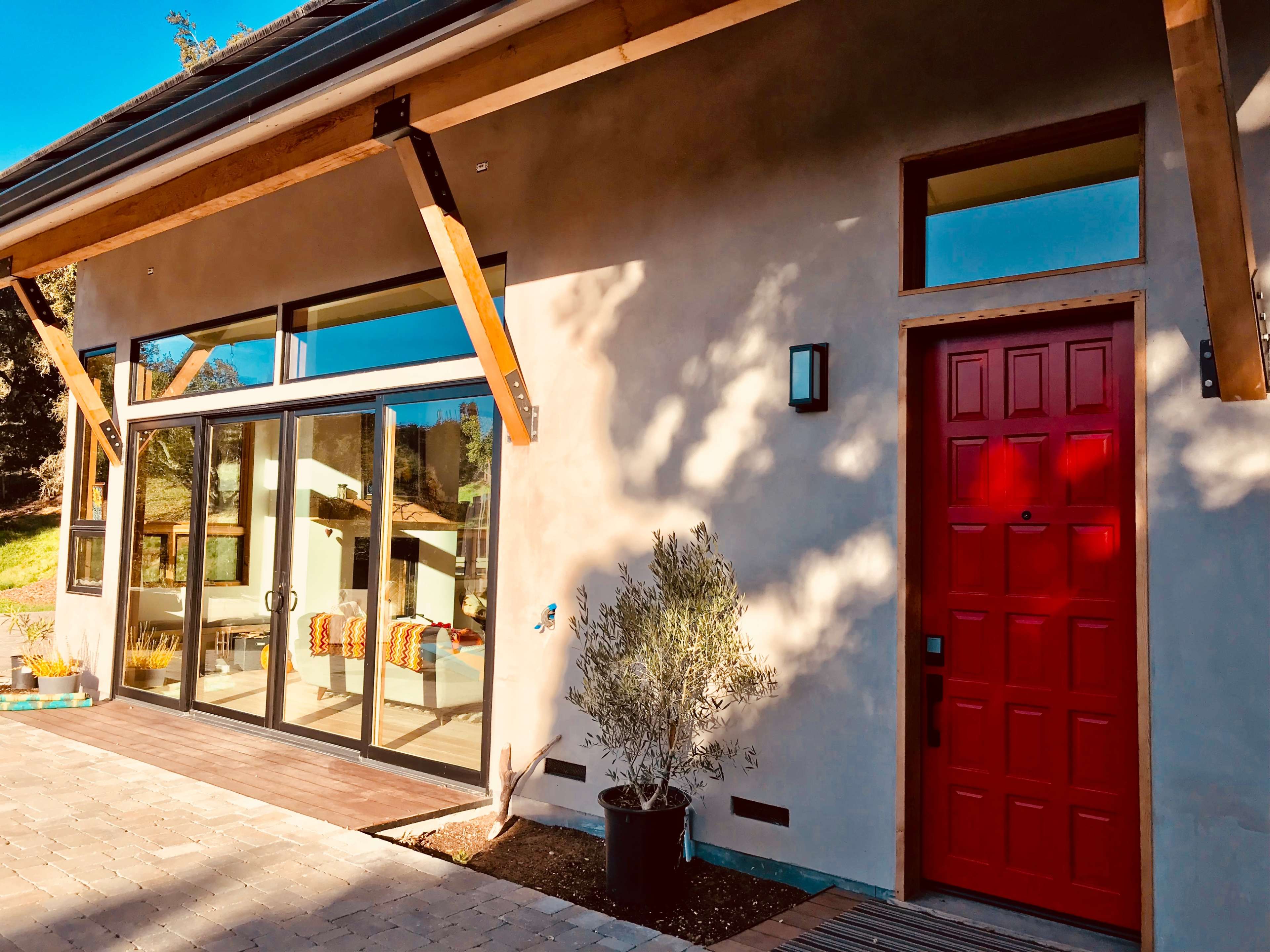 A modern house with a red front door, large glass windows, and a landscaped walkway.