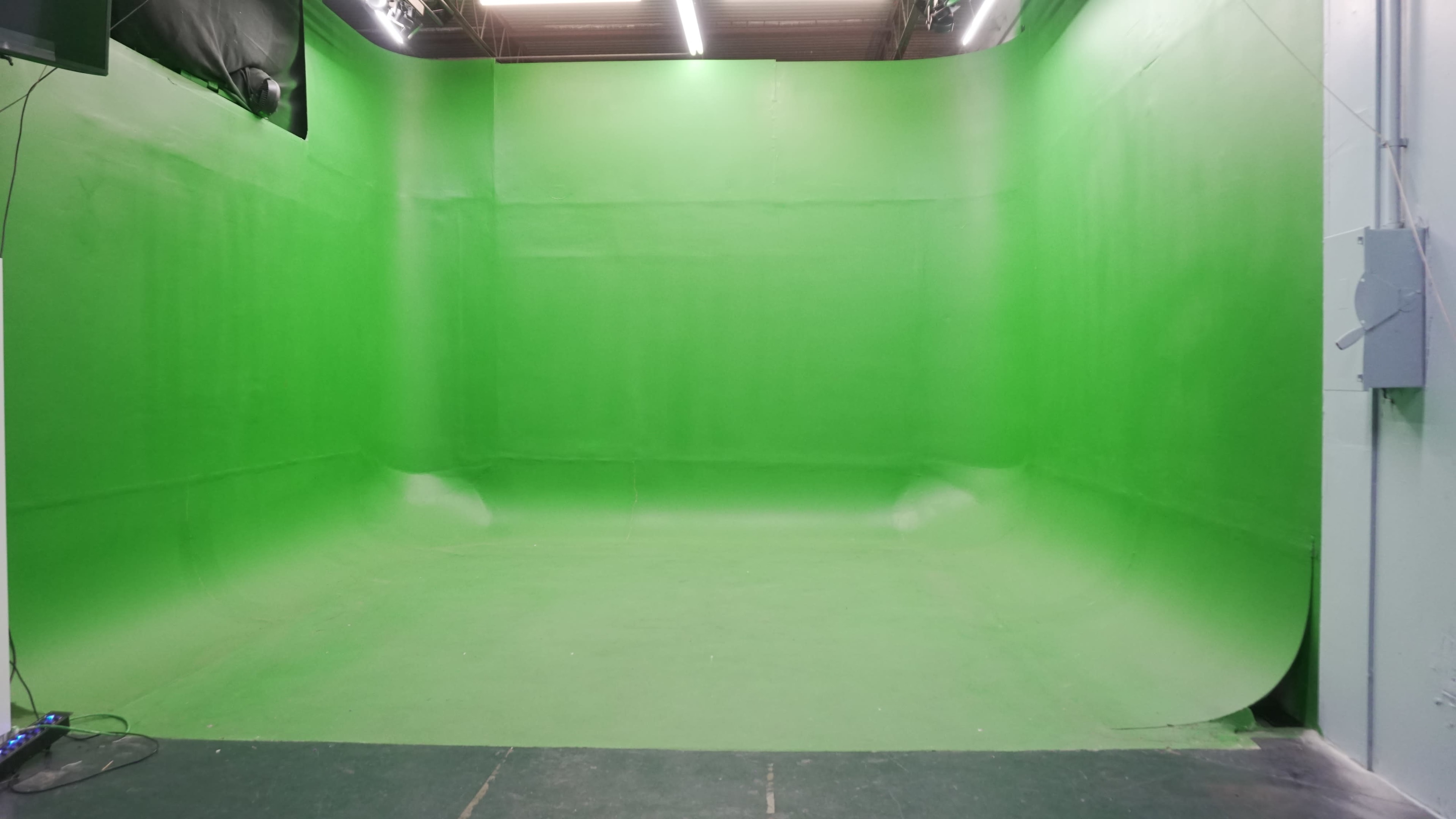 The image shows a large green screen studio with smooth green walls and floor.