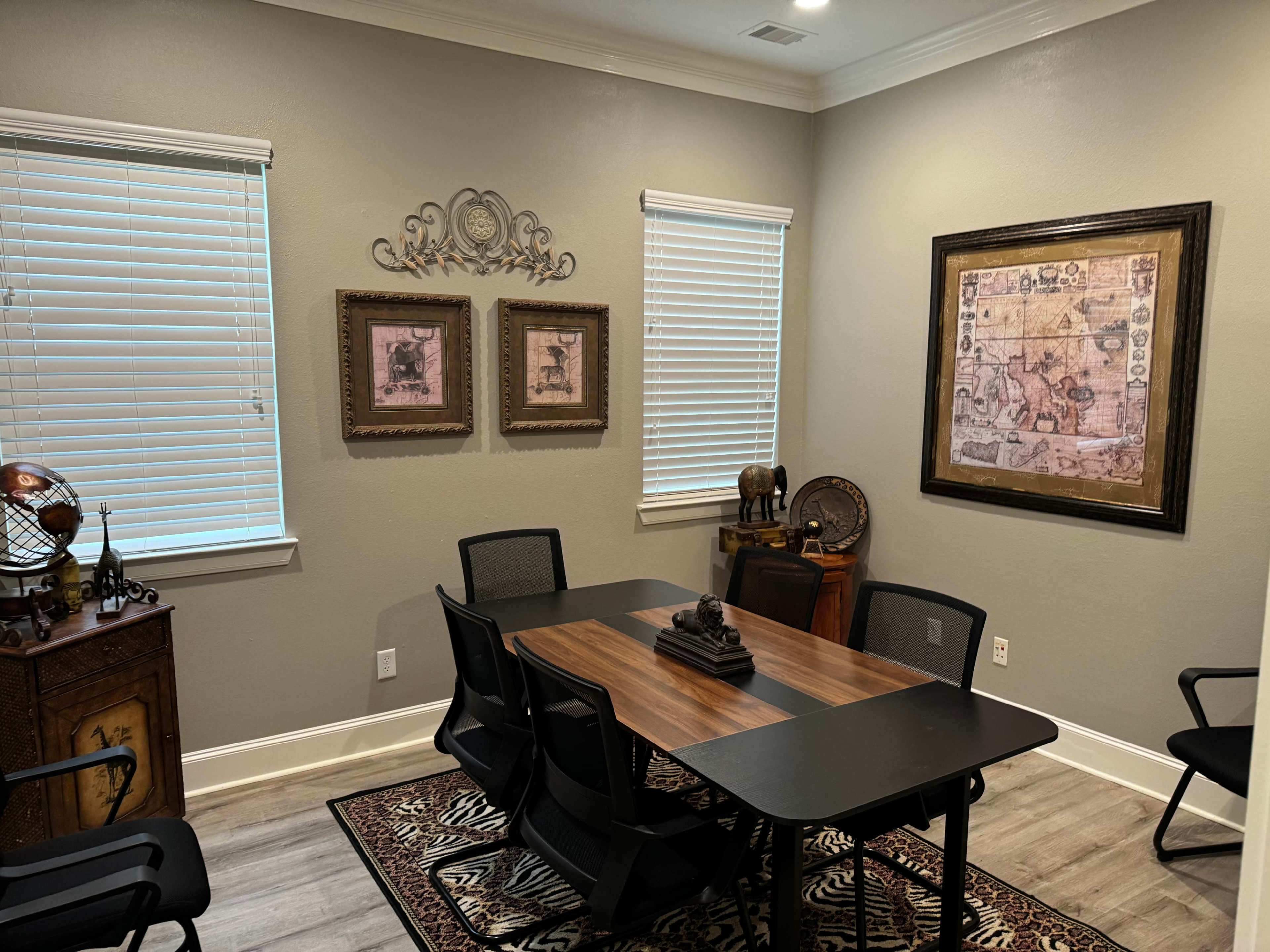 The room features a wooden table surrounded by black chairs, with framed artwork and decorative items on the walls and shelves.
