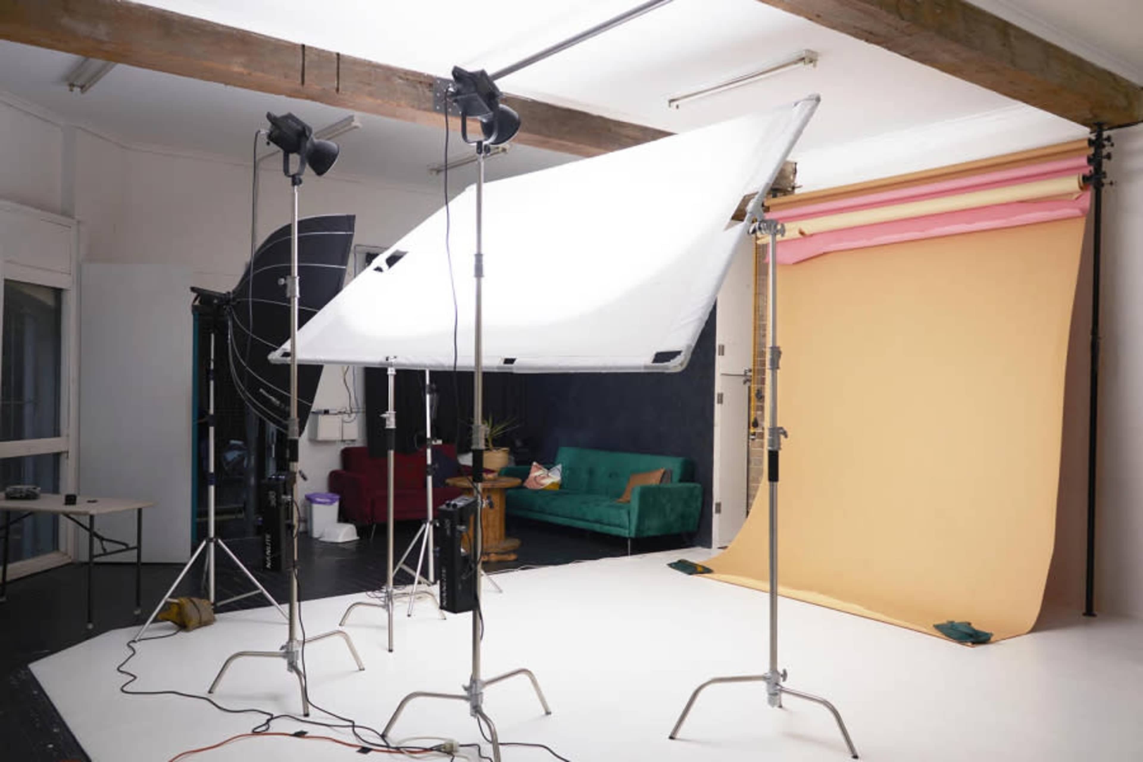 A photography studio with lighting equipment and backdrops in beige and pink colors.