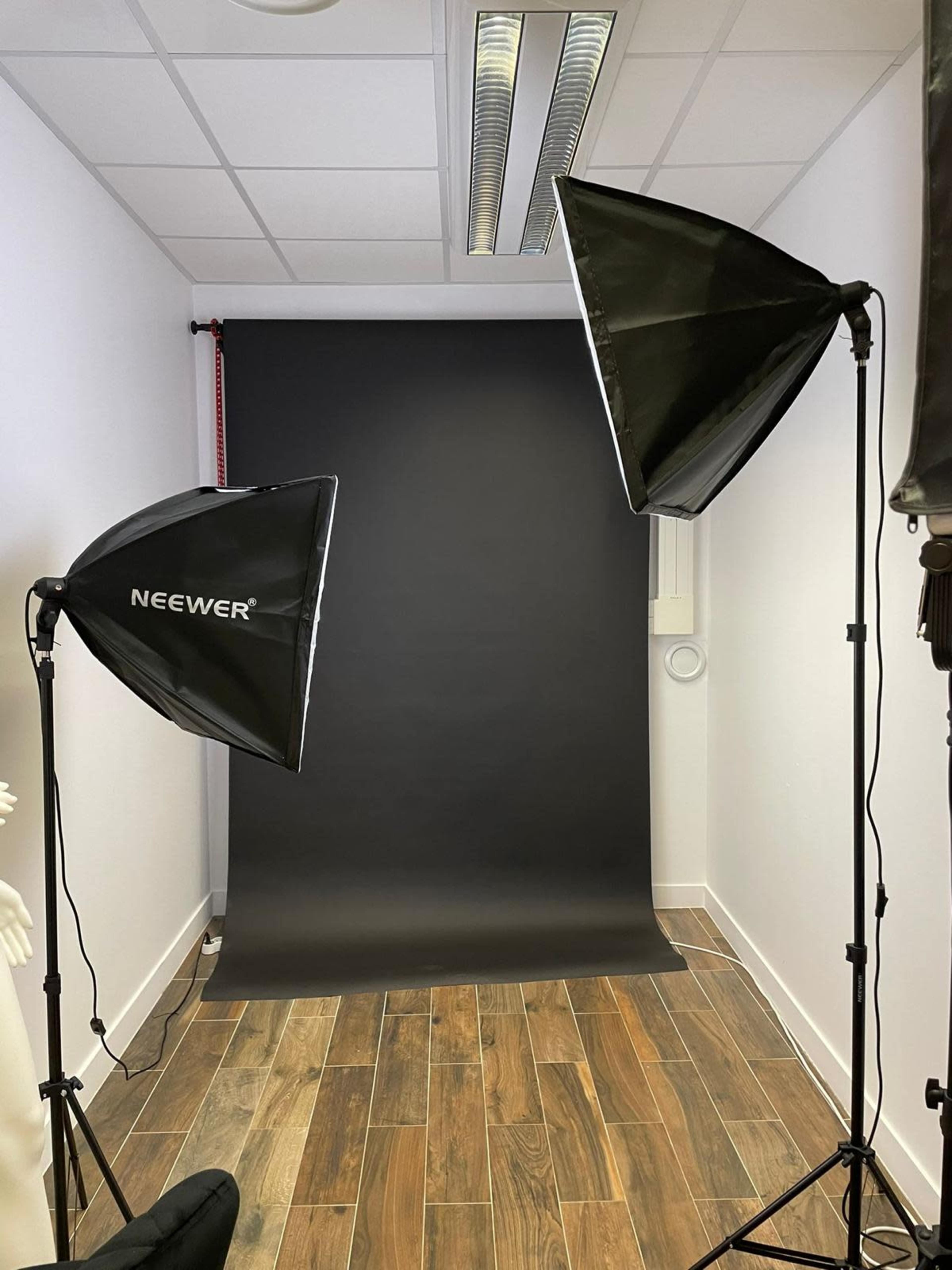 A photography studio featuring two large softbox lights positioned on either side of a black backdrop.