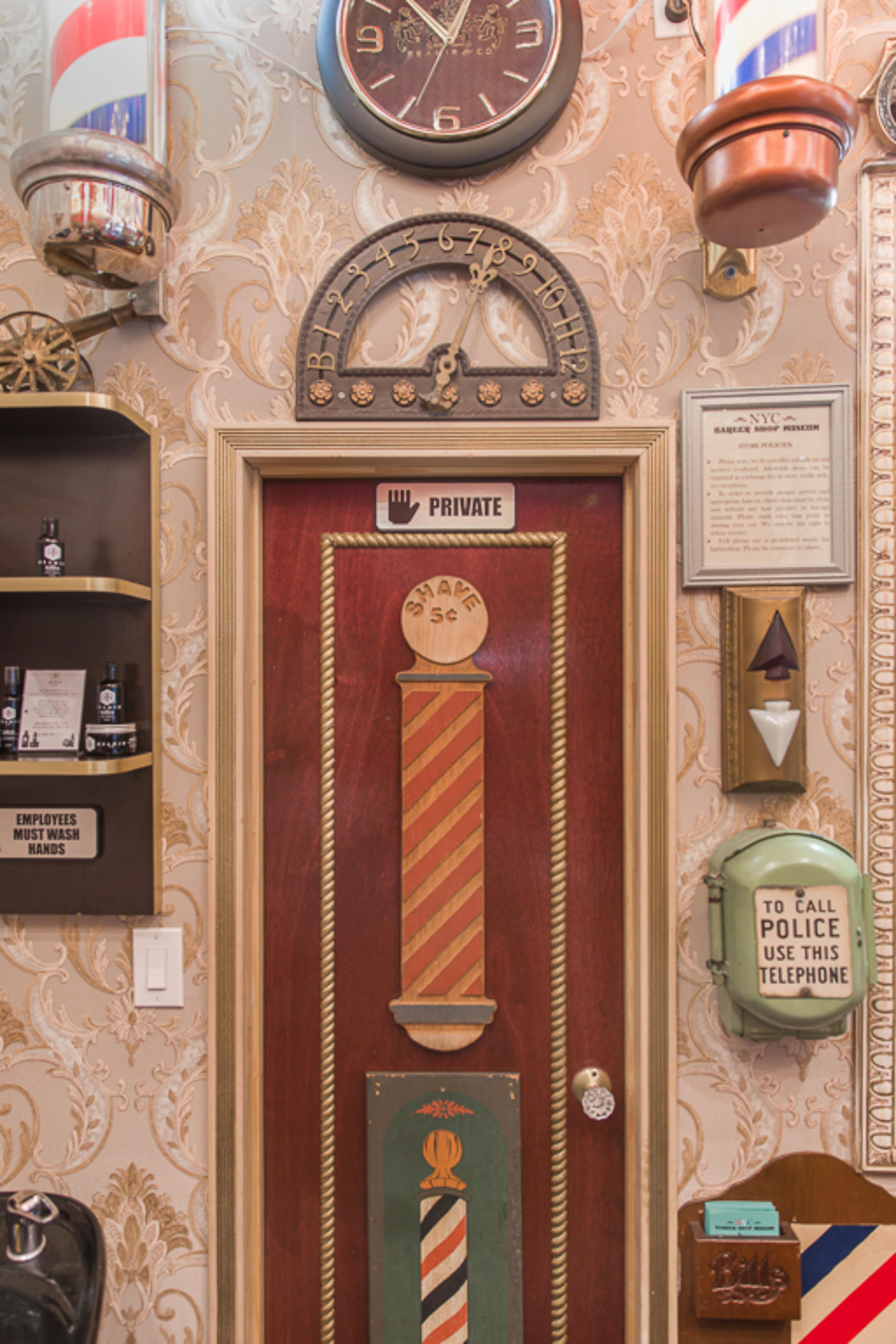 A decorative door with a barber pole design, labeled "PRIVATE," surrounded by various vintage barber shop decor.