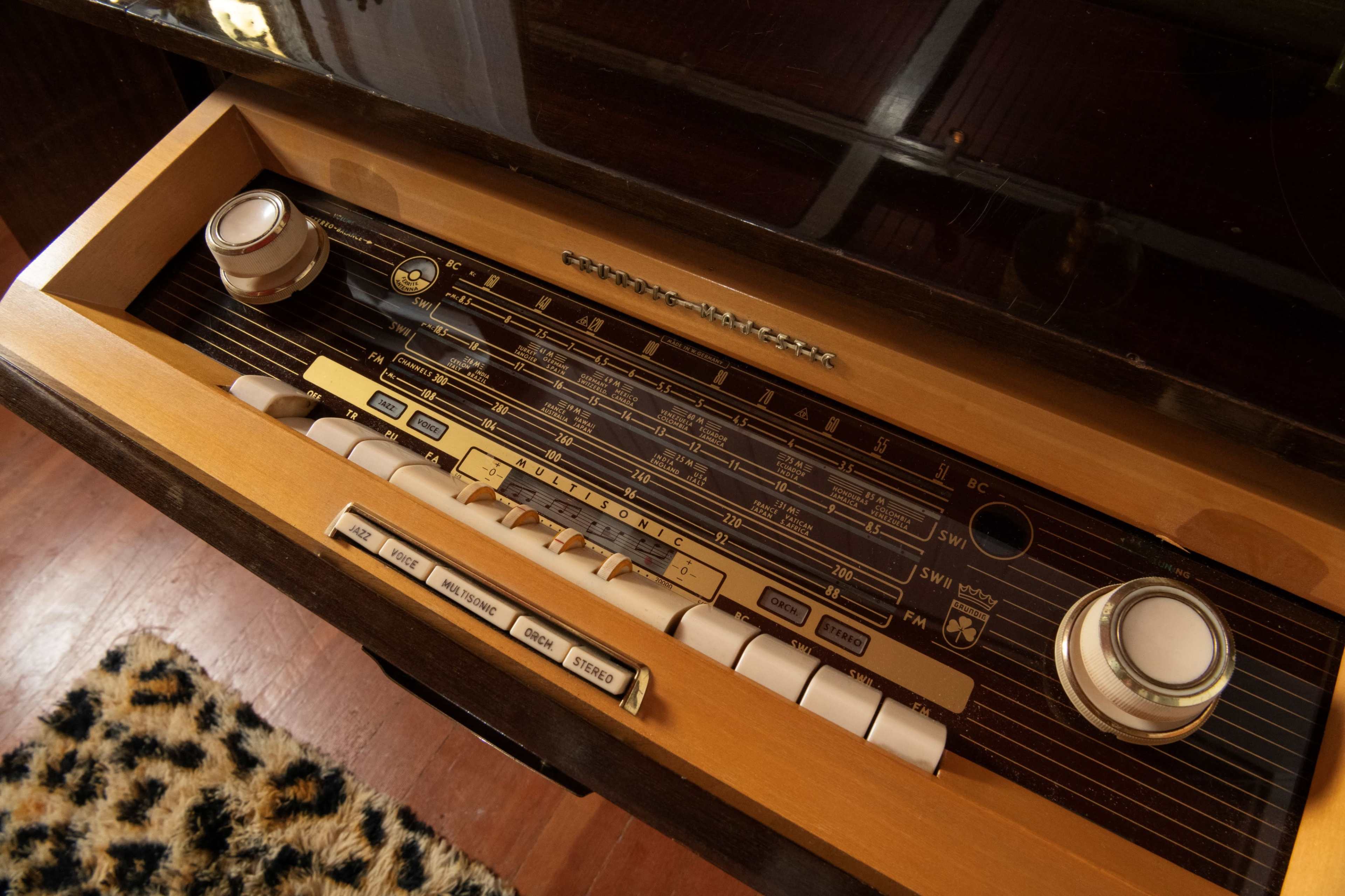 The control panel of a vintage radio with wooden trim and a series of knobs and buttons for tuning and volume adjustment.