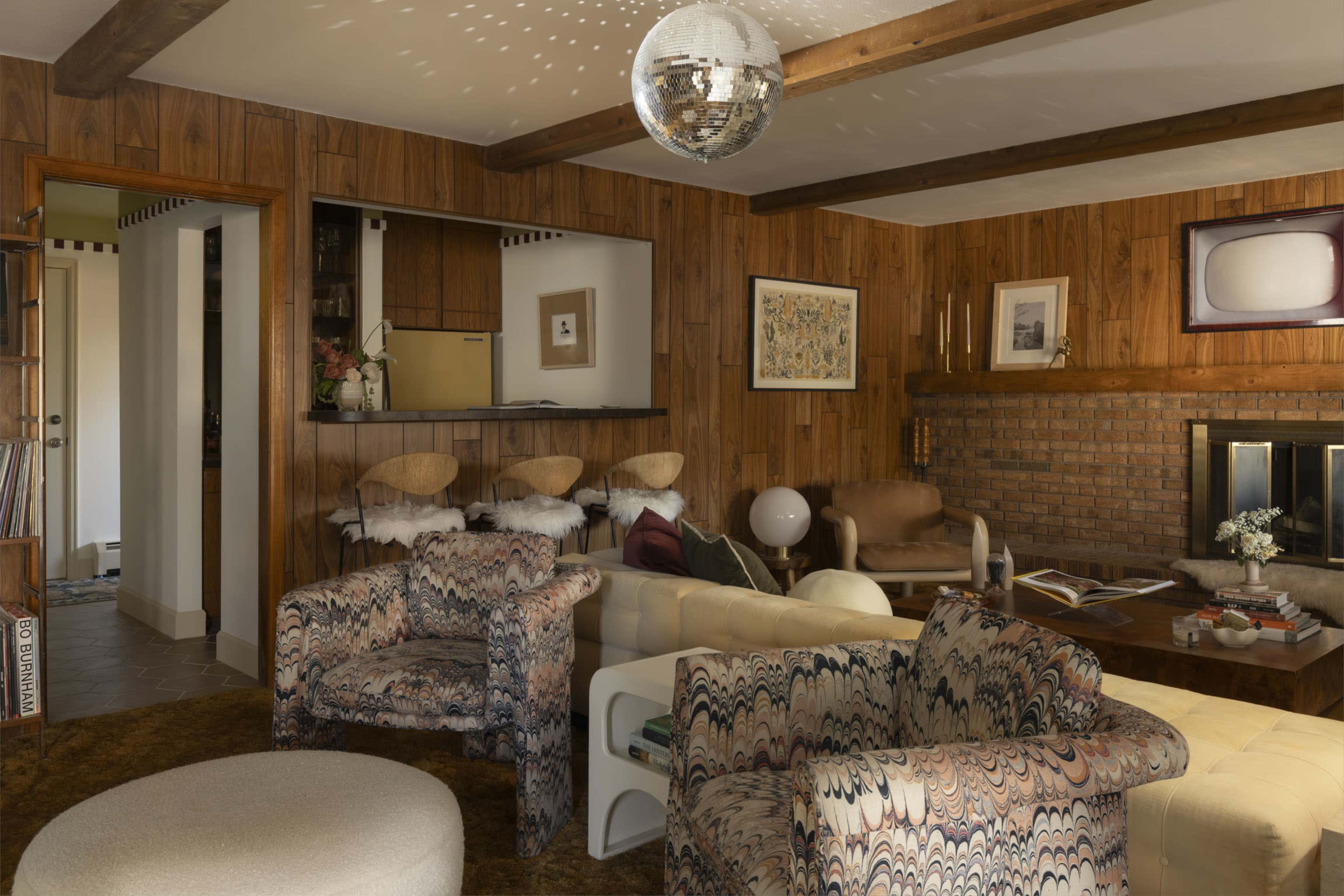 The living room features wooden paneling, vintage furniture, and a disco ball hanging from the ceiling.