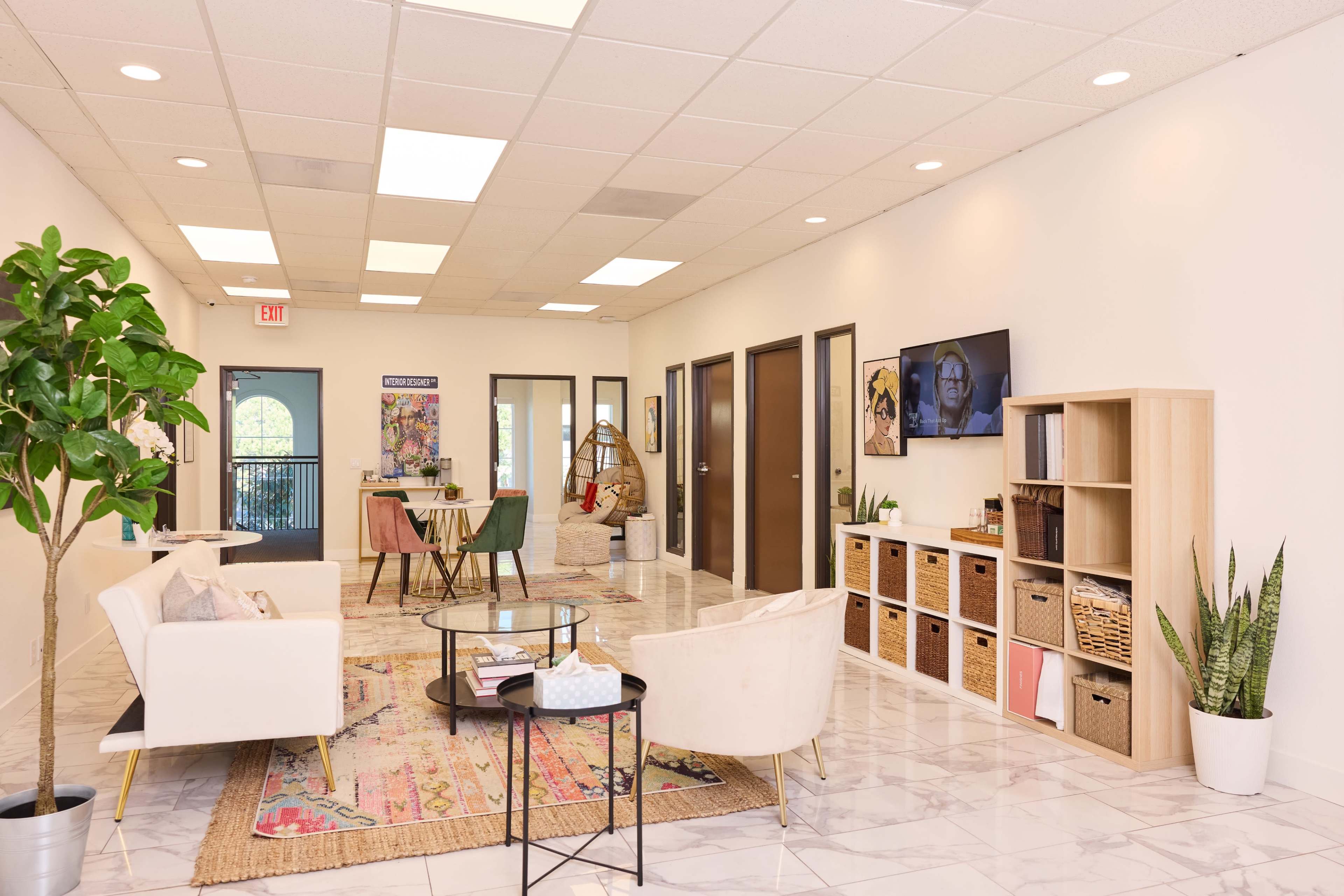 A well-lit office reception area features modern furniture, a decorative rug, and storage units along the walls.